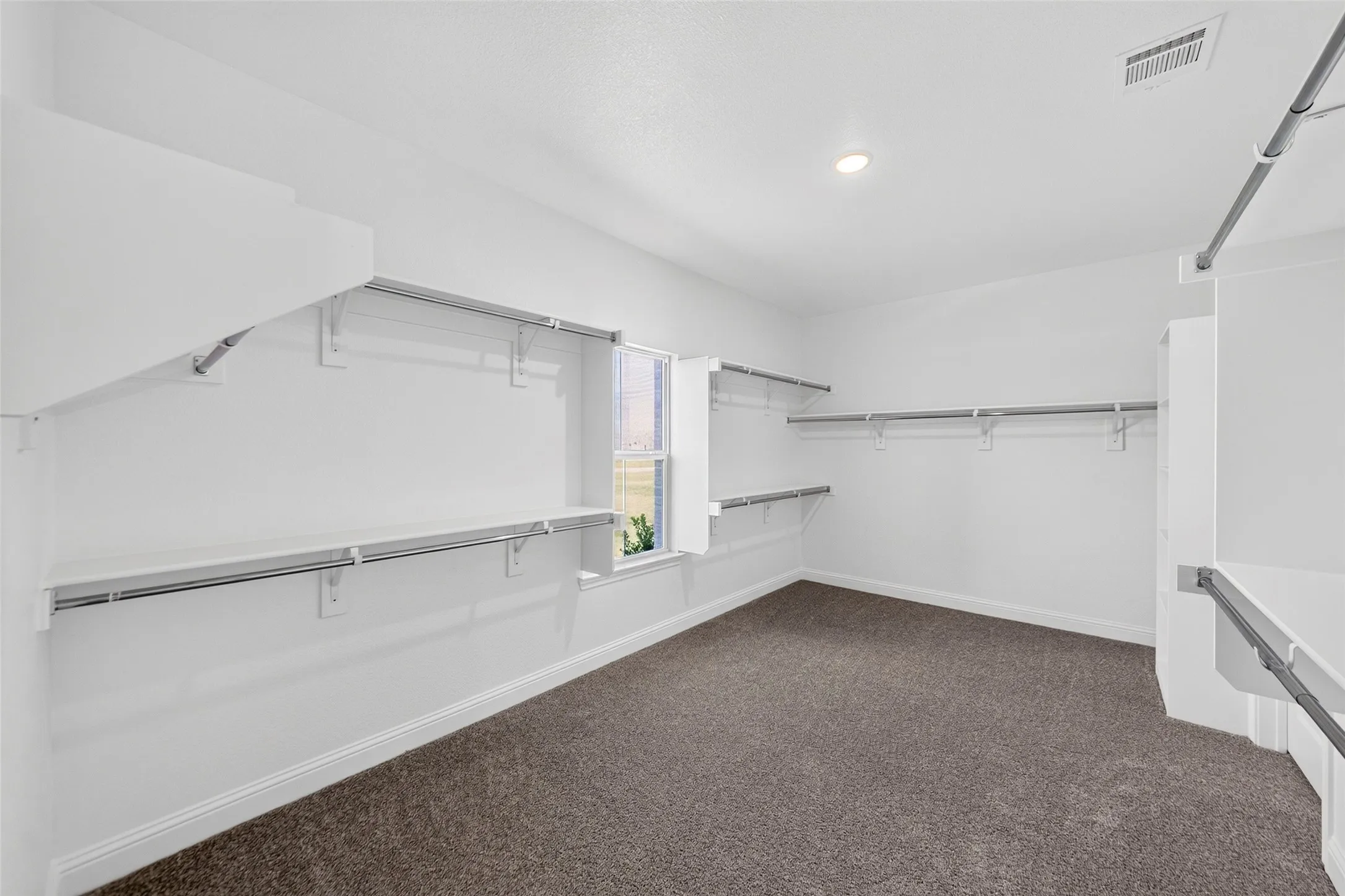 Spacious closet featuring abundant shelving and hanging rods