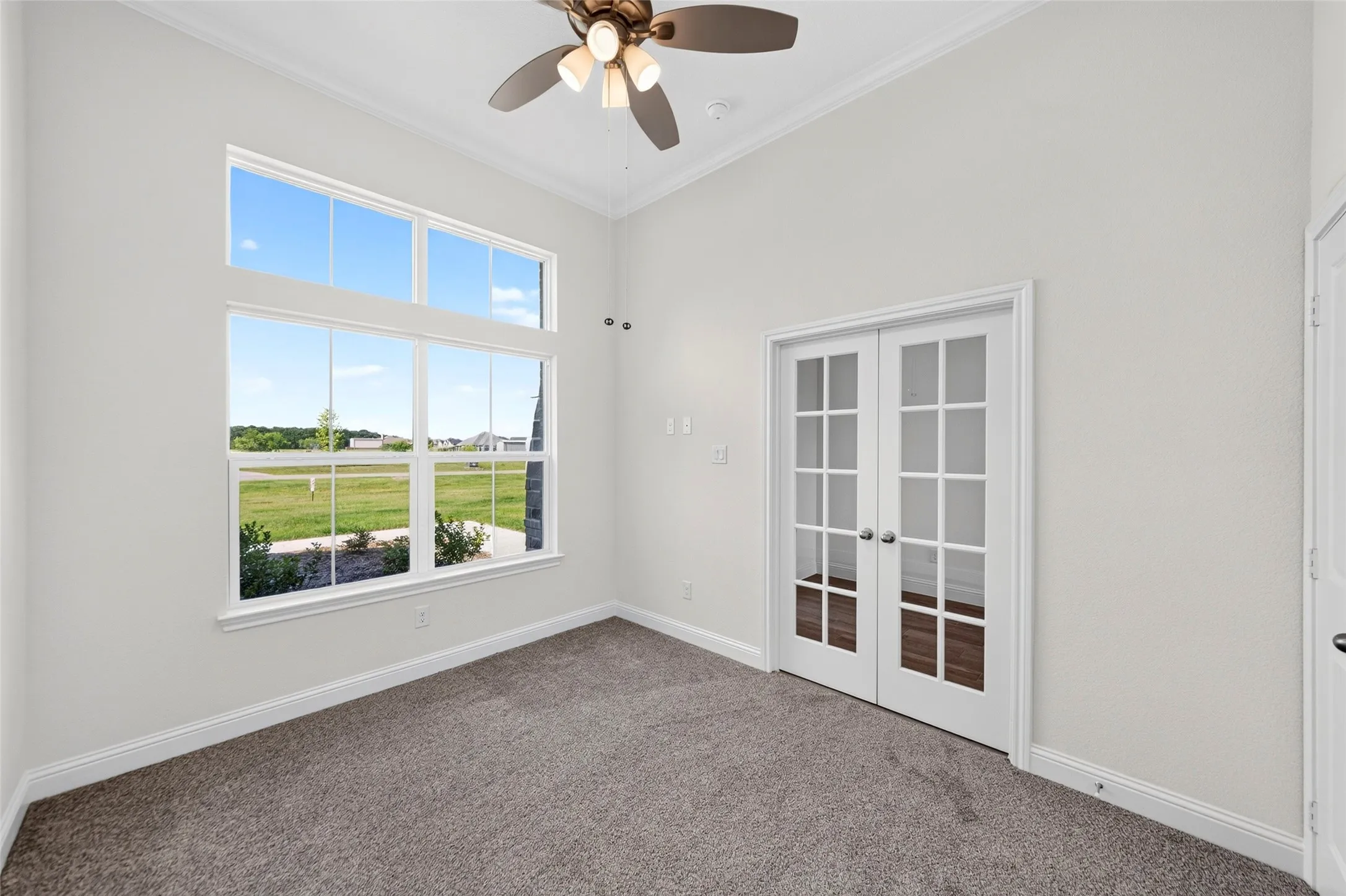 Room featuring a large multi-pane window, vaulted ceiling, and dual French doors with glass panels