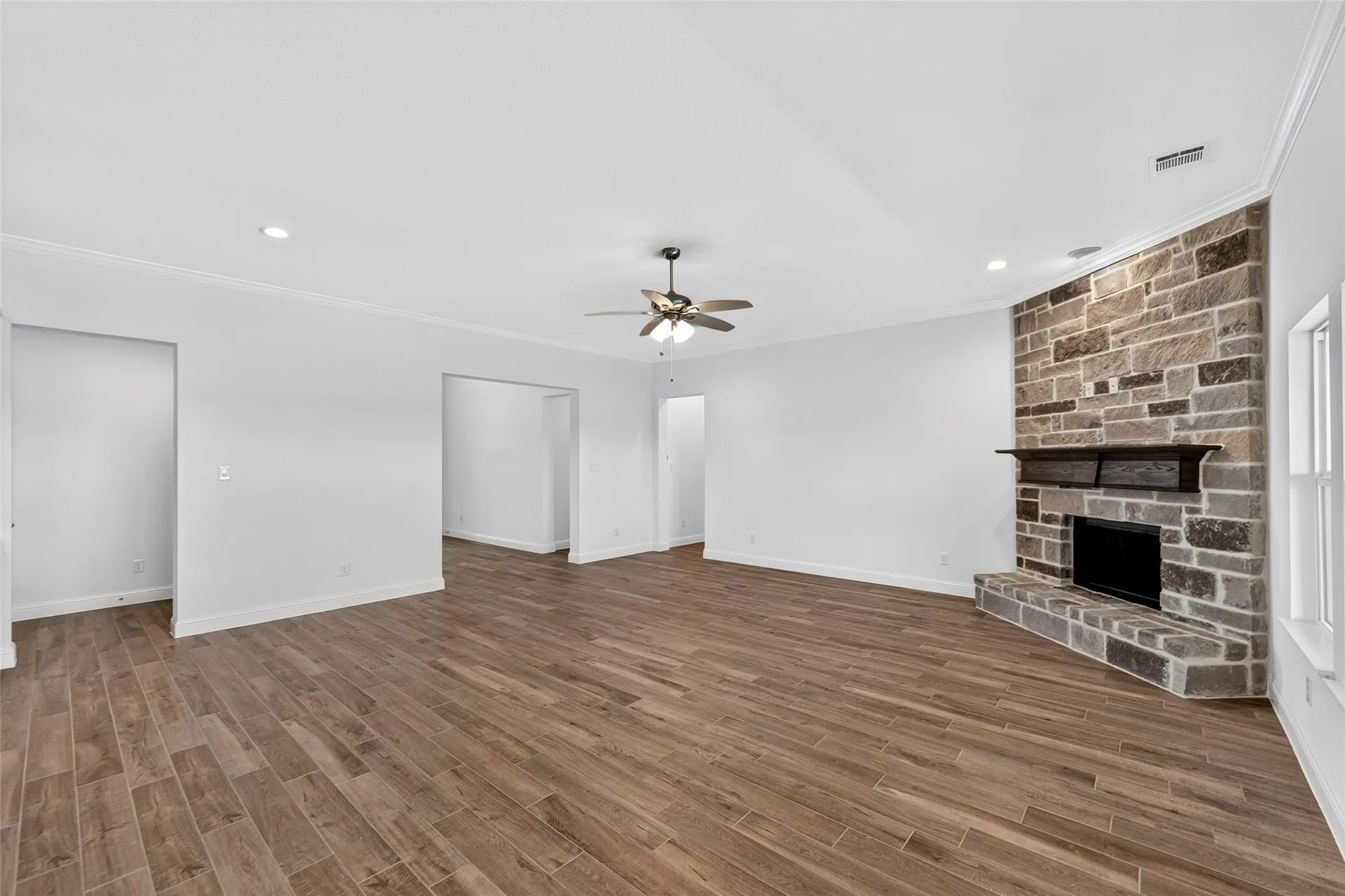 Living area featuring wood-finish flooring and a stone fireplace with a dark wood mantle