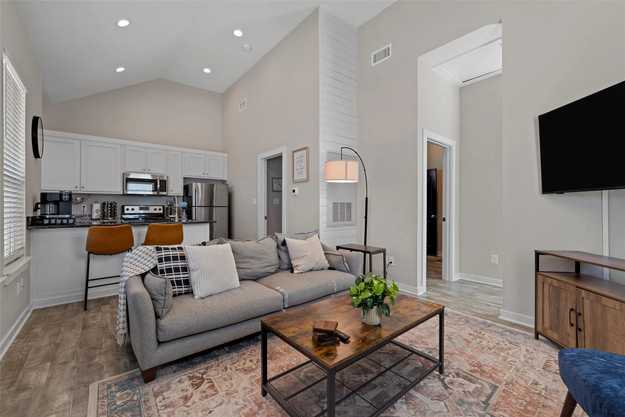 Open-concept living space featuring vaulted ceilings, wood-finish flooring, and recessed lighting