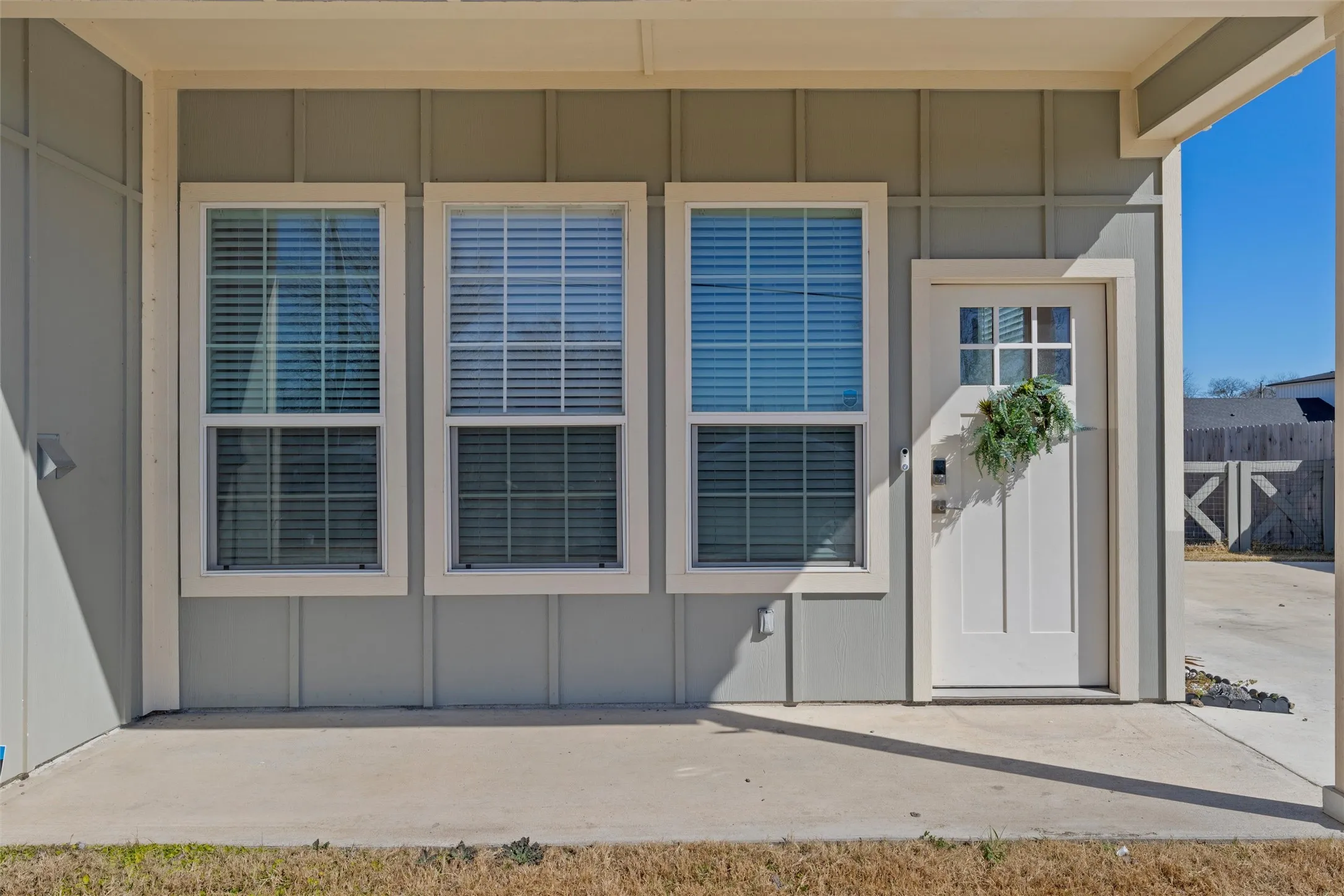 Inviting covered porch entry with a white paneled door featuring upper-level lites