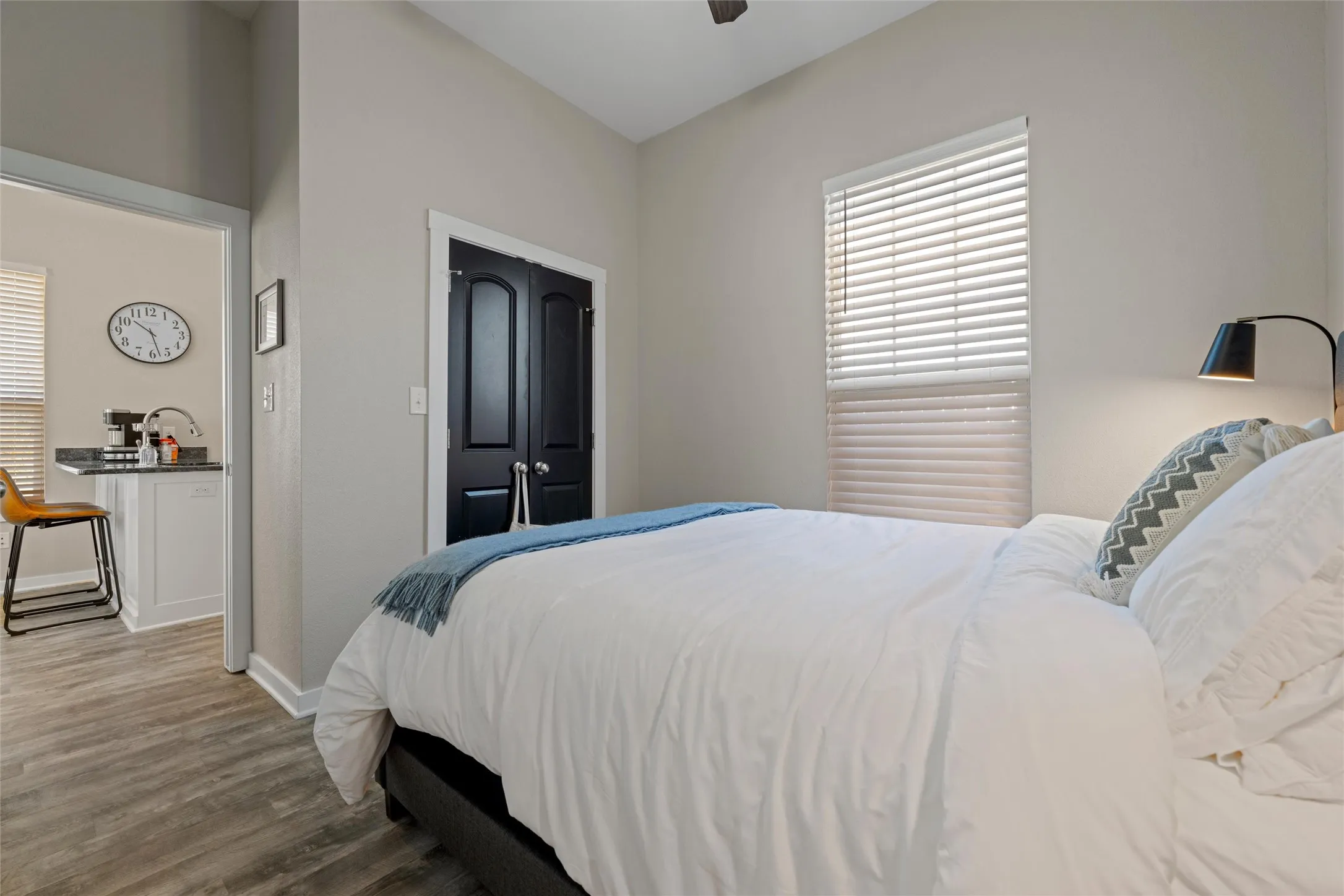 Bedroom featuring wood-finish flooring, a window with horizontal blinds, and a built-in closet with dark paneled doors