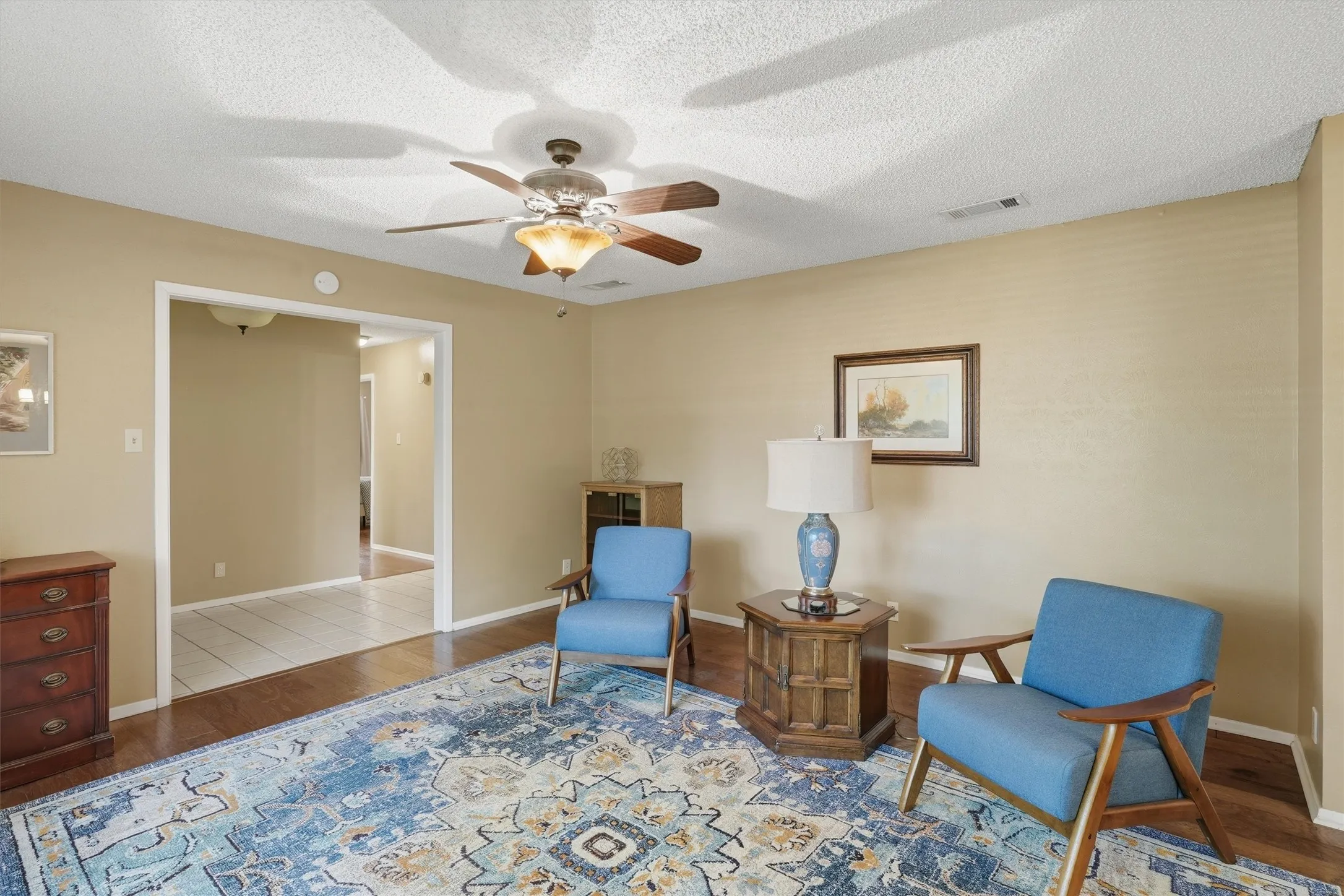 Living area featuring wood flooring, a ceiling fan with integrated lighting, and neutral wall tones