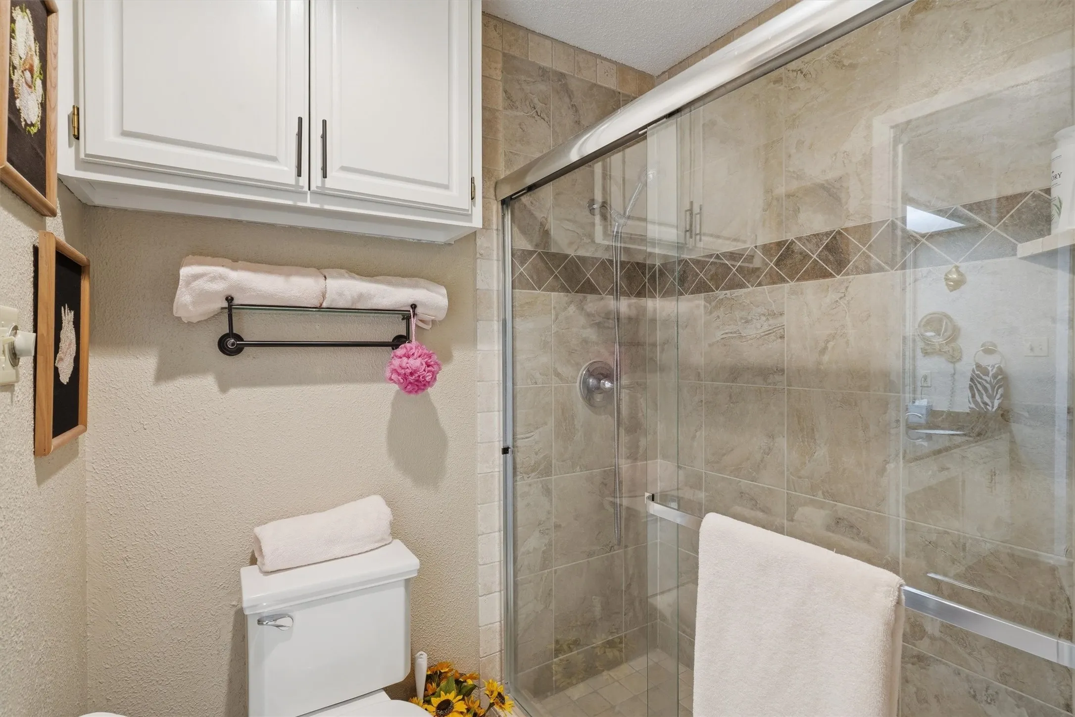 Glass-enclosed shower with tiled walls and a decorative accent band