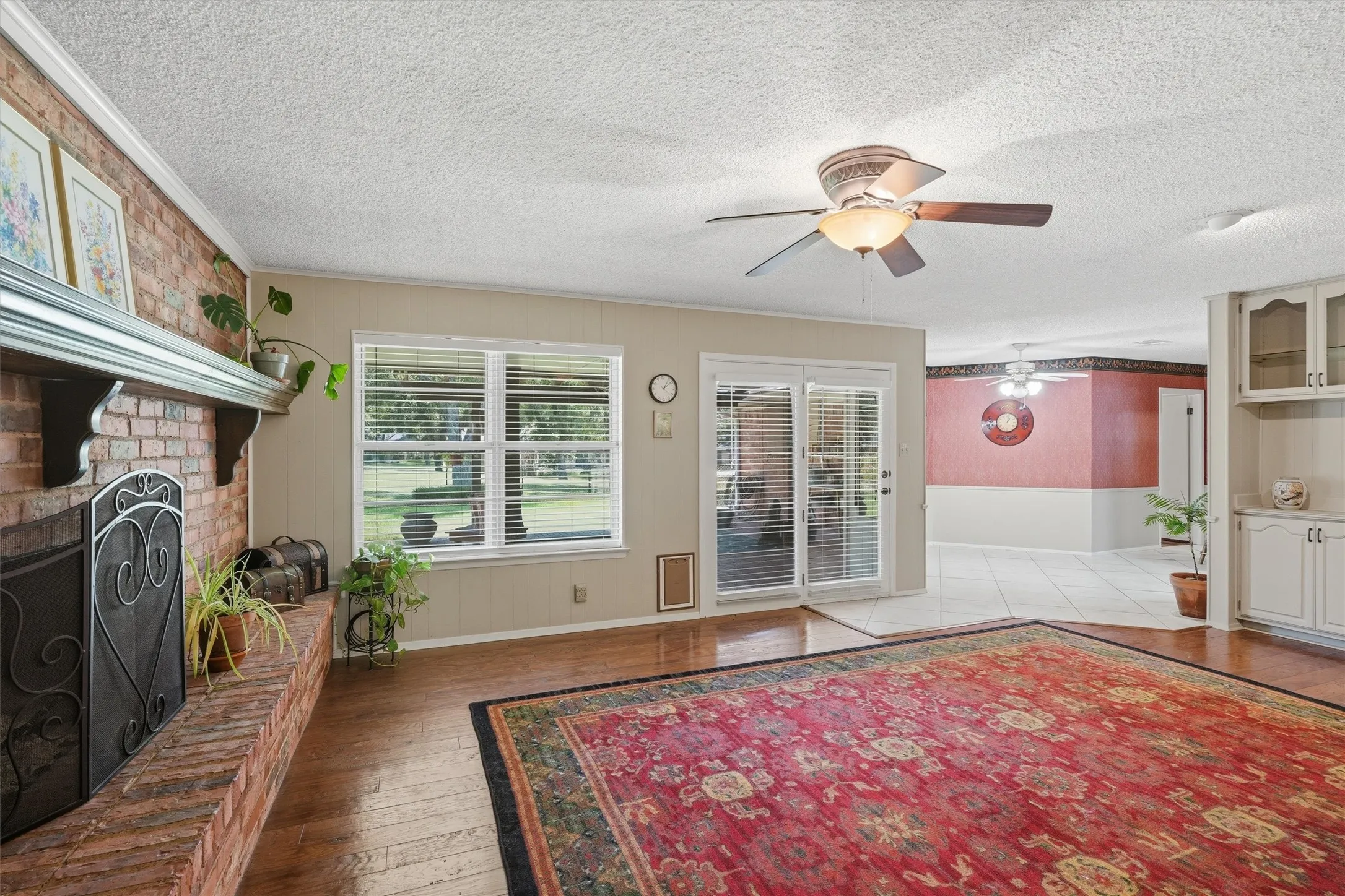 Living area featuring a brick fireplace, wood-finish flooring, and white window blinds
