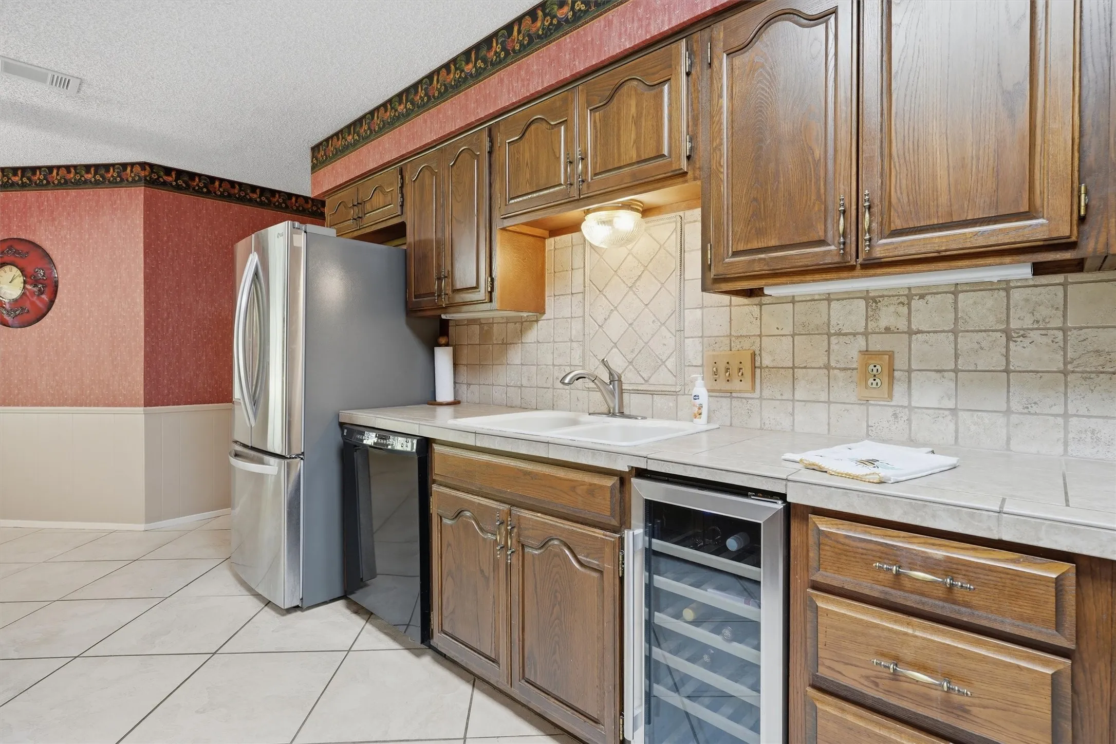 Kitchen featuring wood cabinetry, a tiled backsplash, and light-toned tile flooring