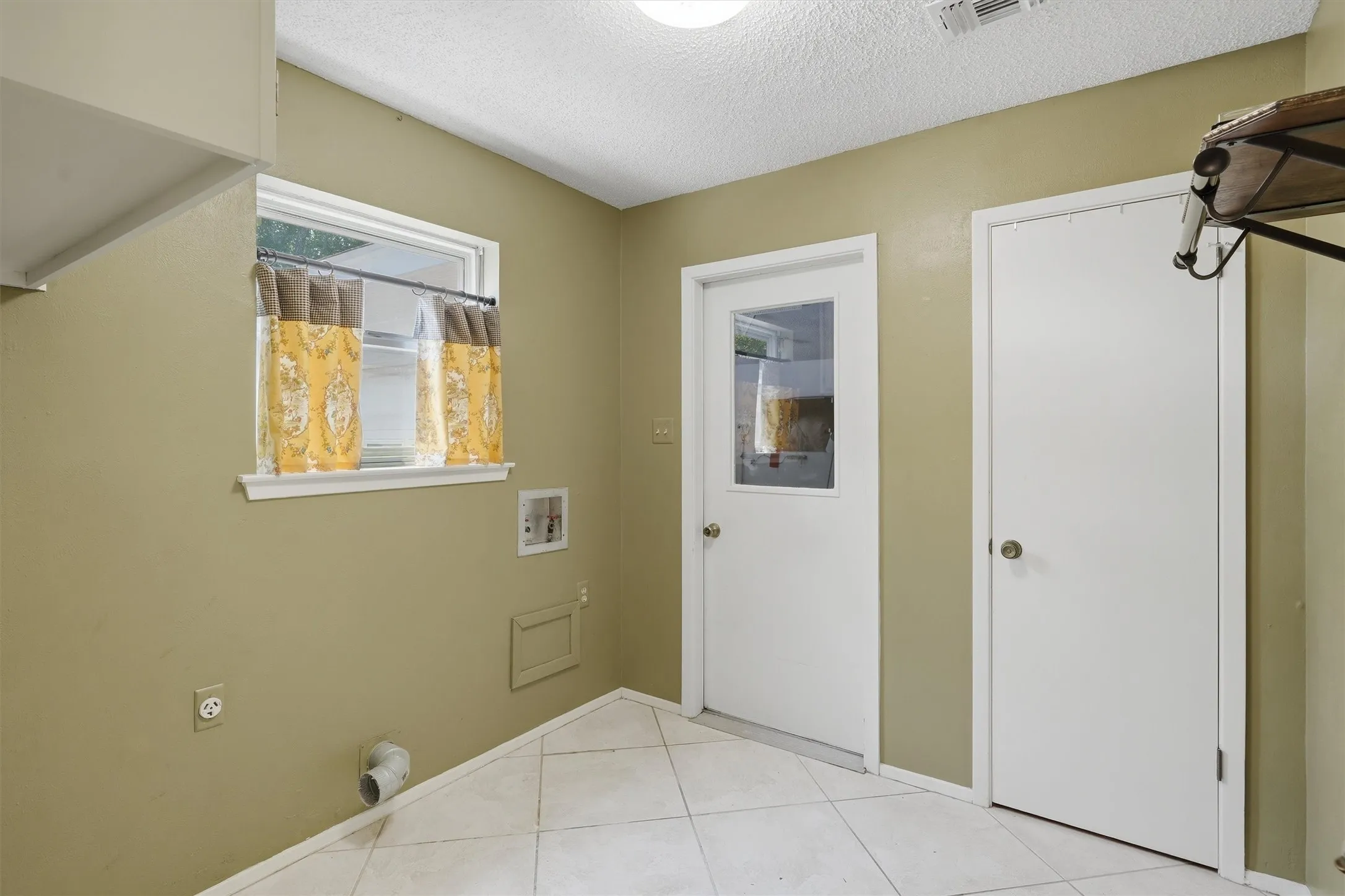 Laundry area featuring a window, tile flooring, and utility hookups