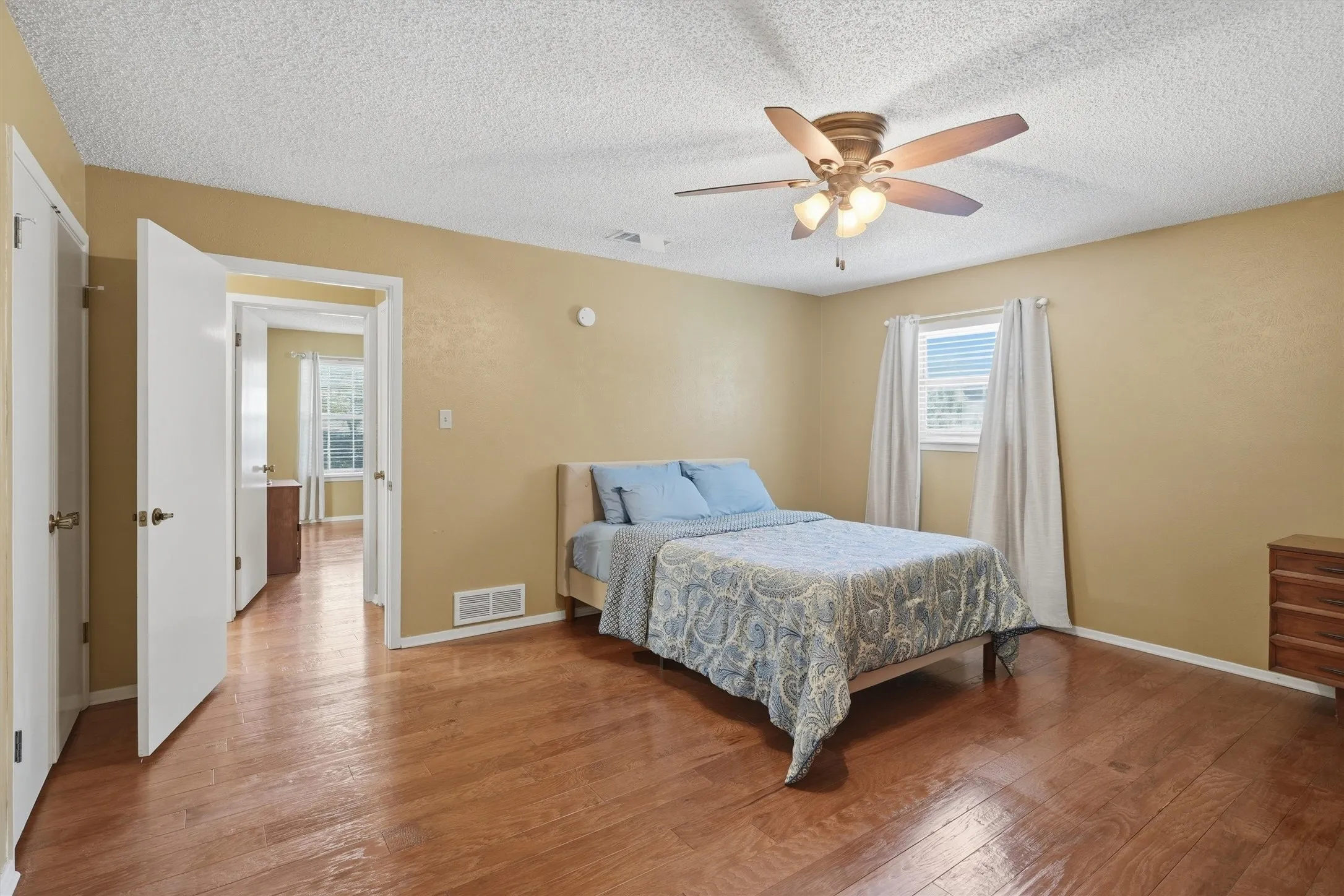 Room featuring wood flooring, a ceiling fan with integrated lighting, and a window with blinds