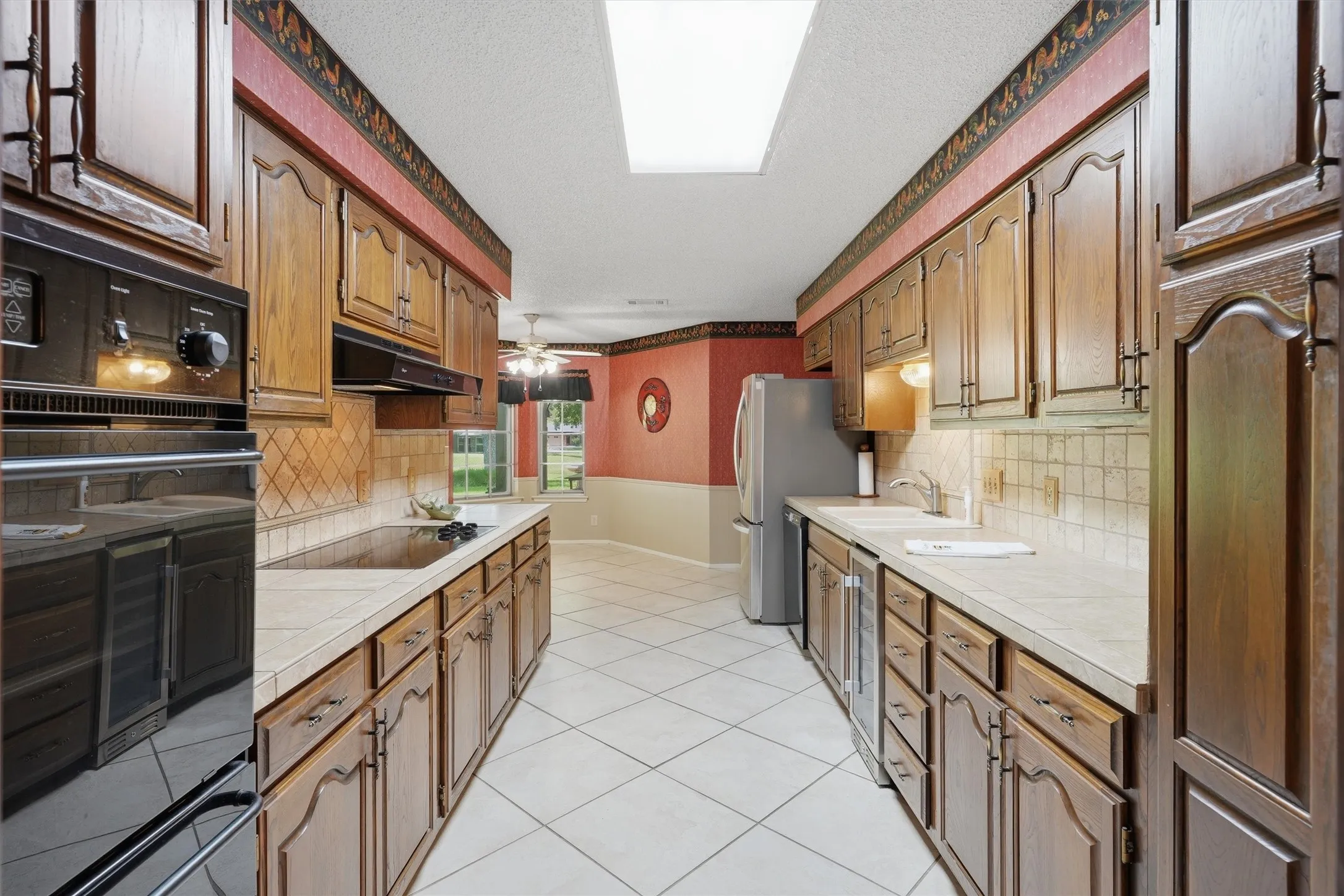 Galley kitchen featuring extensive wood cabinetry, an integrated wall oven, and a built-in cooktop