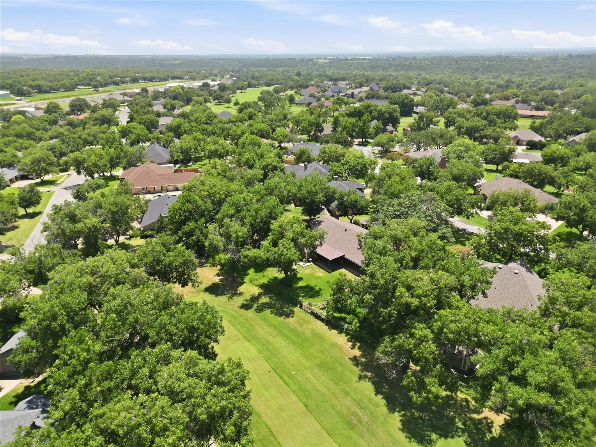 Expansive aerial overview showcasing a residential area with mature tree coverage and manicured green spaces