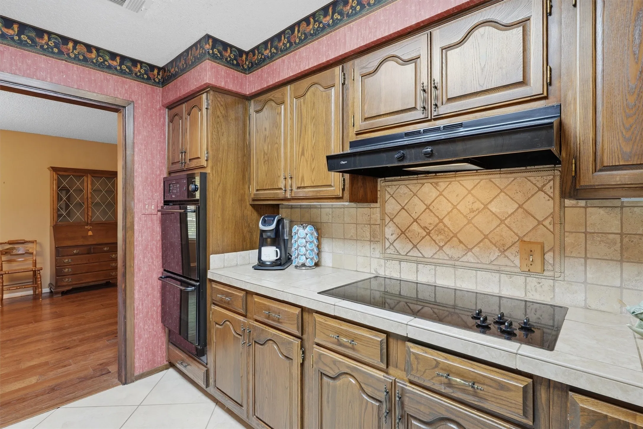 Kitchen featuring wood cabinetry, integrated double ovens, and a black cooktop