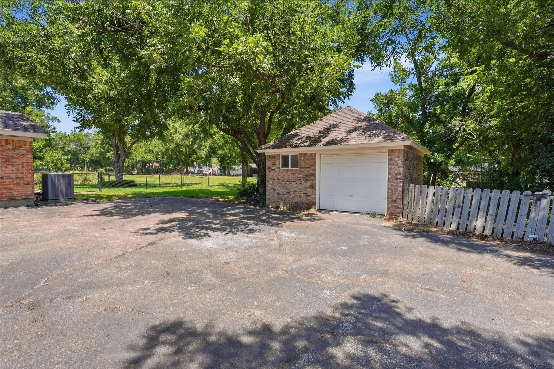 Detached single-car or golf cart garage with brick exterior and asphalt shingle roof