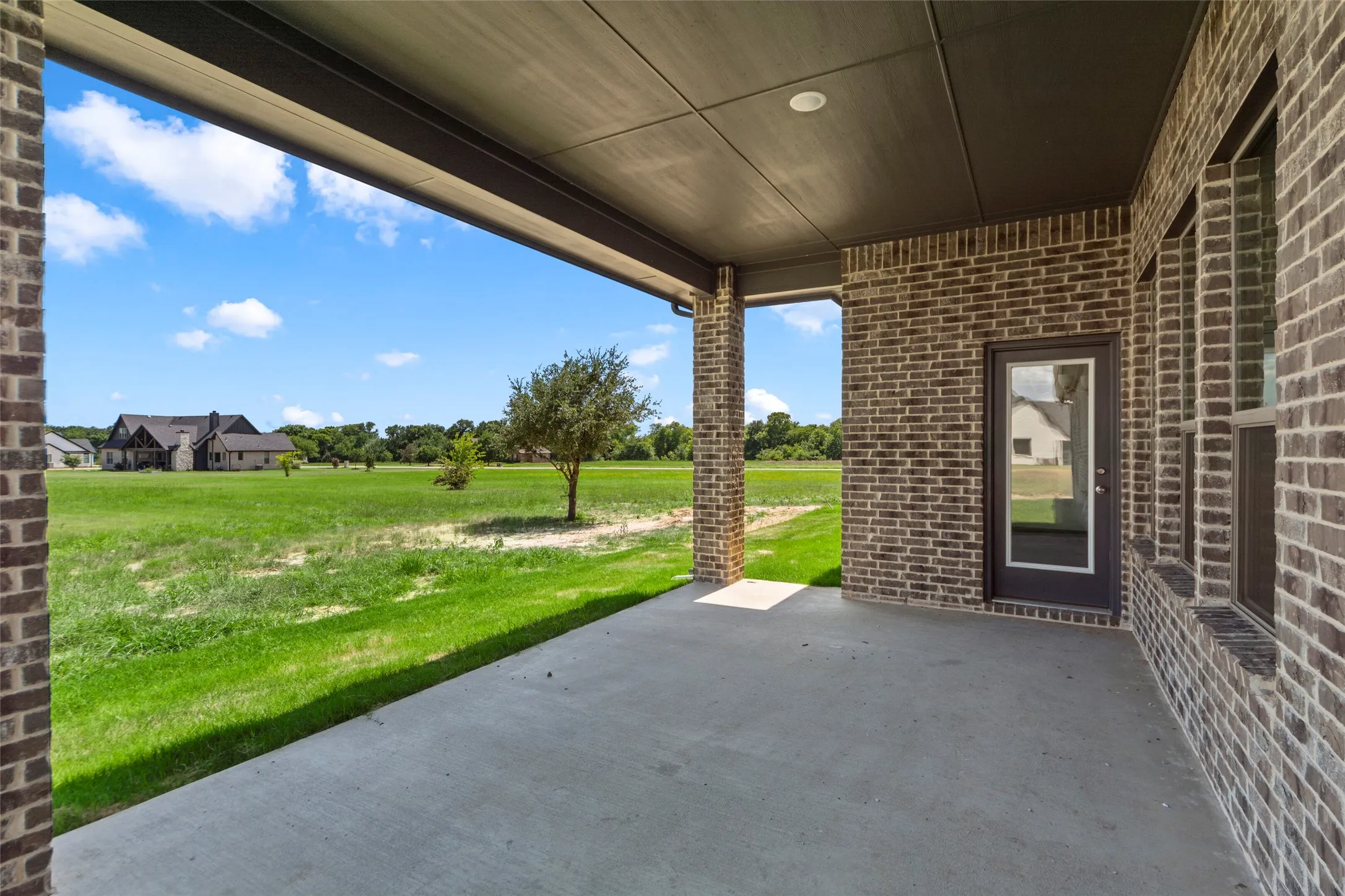 Concrete patio featuring a brick exterior, recessed lighting, and a glass-paneled exterior door