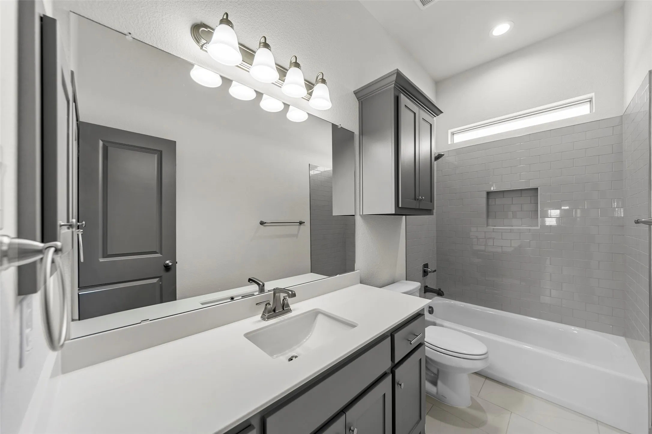 Full-width vanity mirror reflecting a gray paneled door