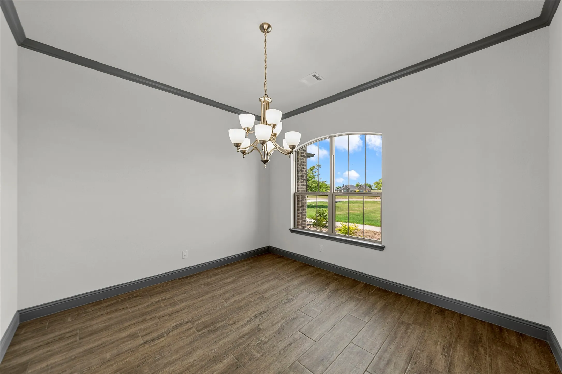 Room featuring wood-look tile flooring, gray baseboards, and gray crown molding