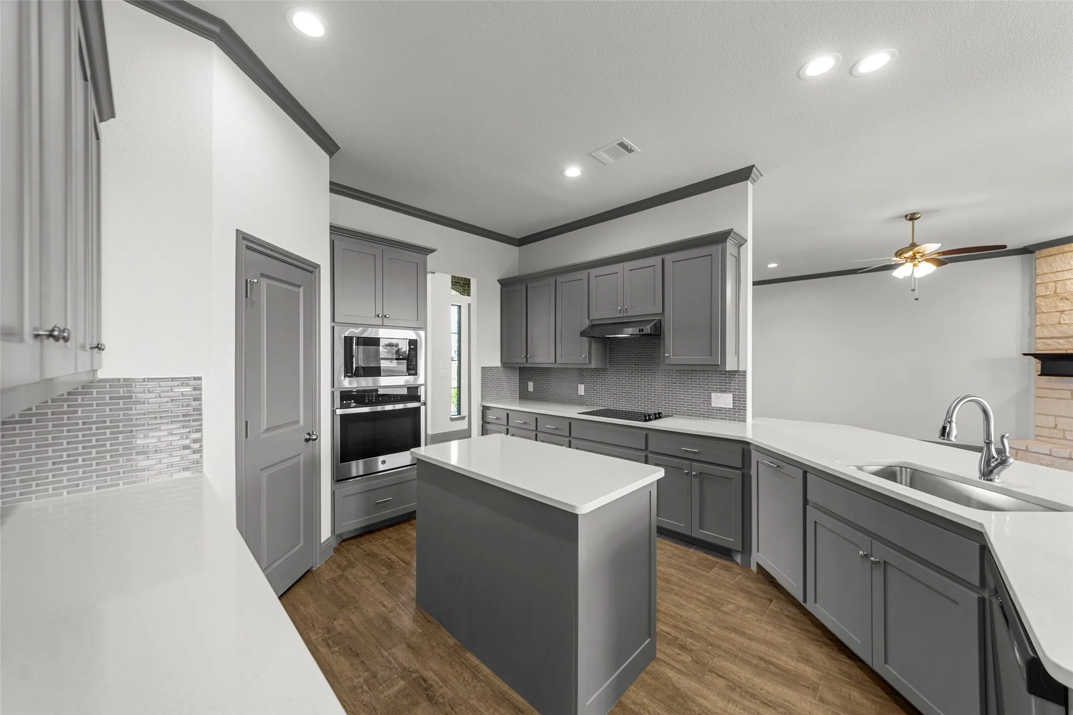 Kitchen featuring an island with a white countertop, gray cabinetry, stainless steel appliances, wood-finish flooring, and recessed lighting