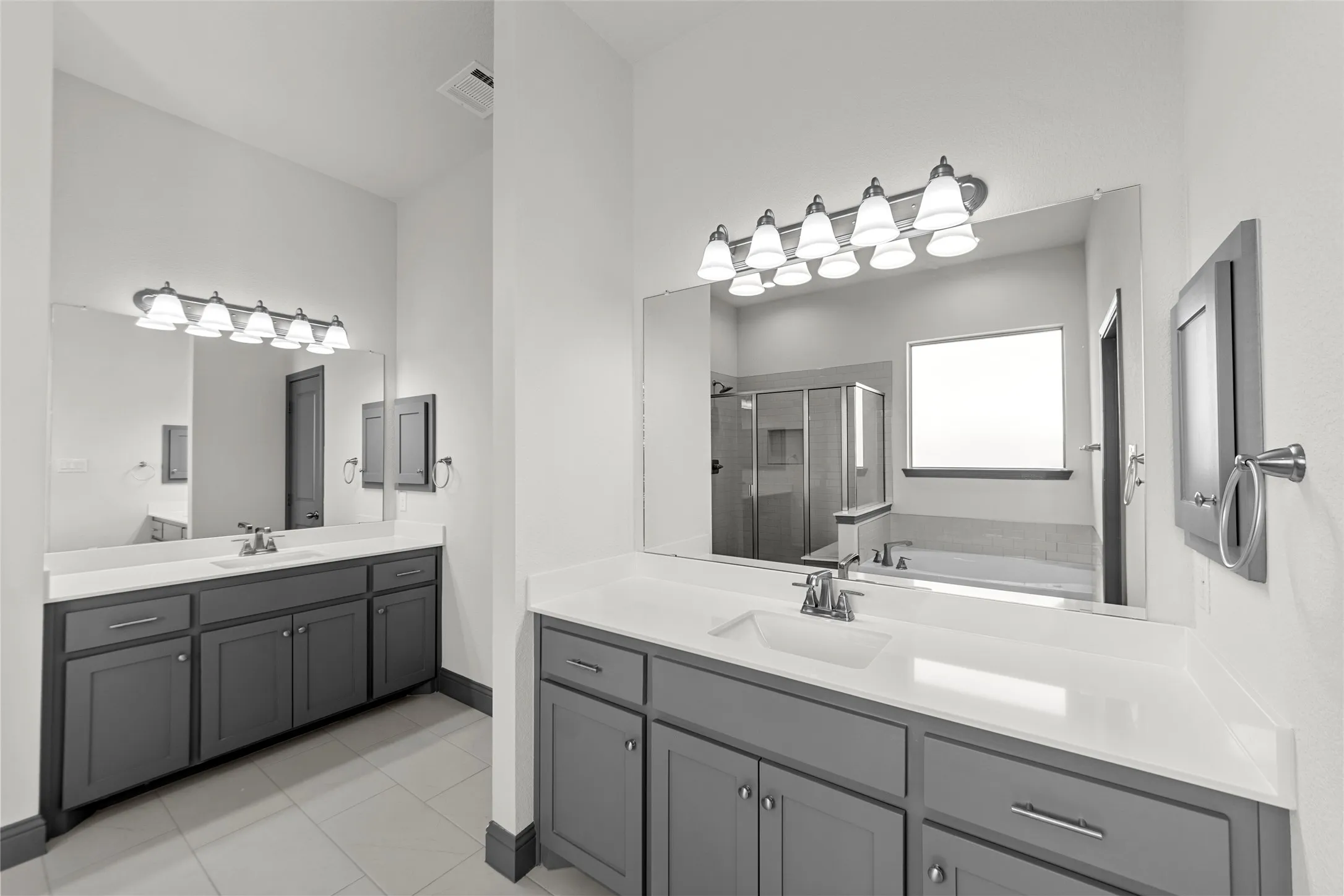 Dual vanities featuring gray cabinetry and white countertops