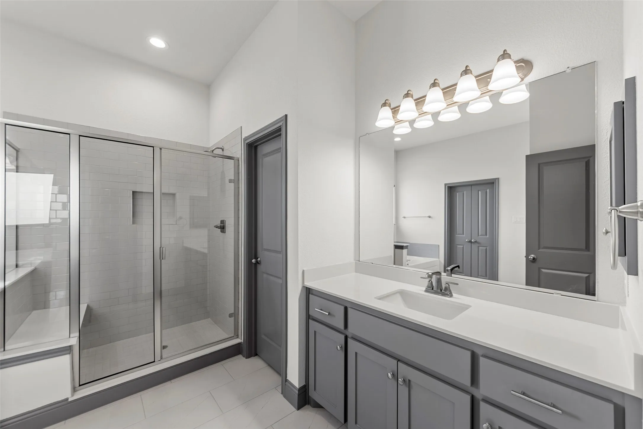 Spacious bathroom featuring a glass-enclosed shower with subway tile, built-in shower bench, and recessed shelf