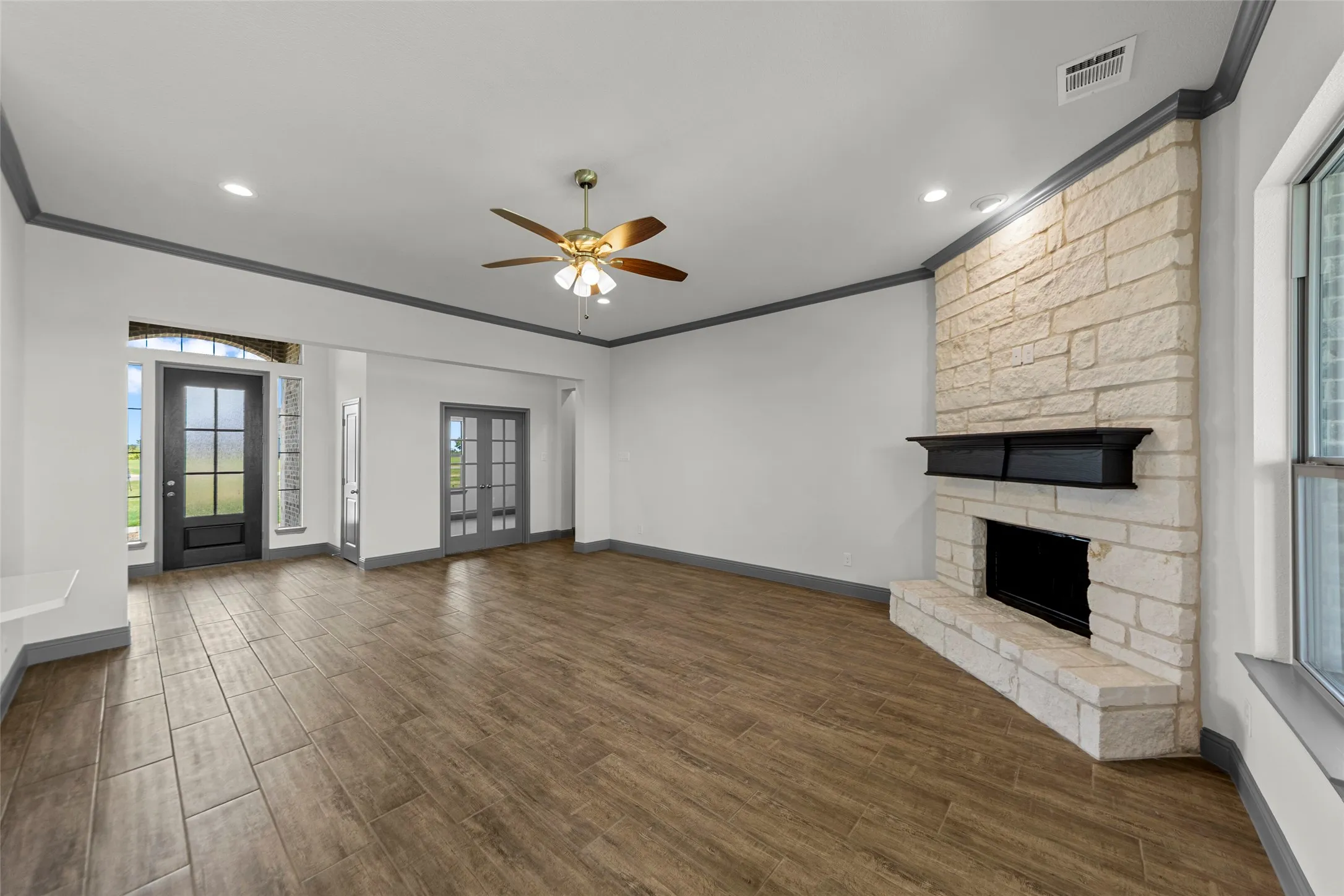 Spacious living area featuring wood-finish flooring, a ceiling fan, and recessed lighting