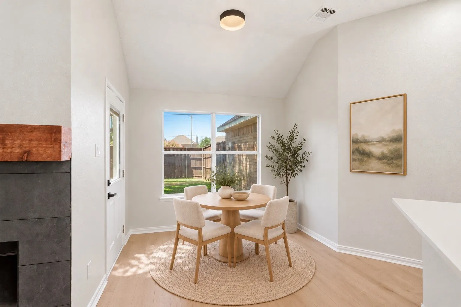 Vaulted ceiling, recessed lighting, wood-finish flooring, white trim, and a window providing natural illumination