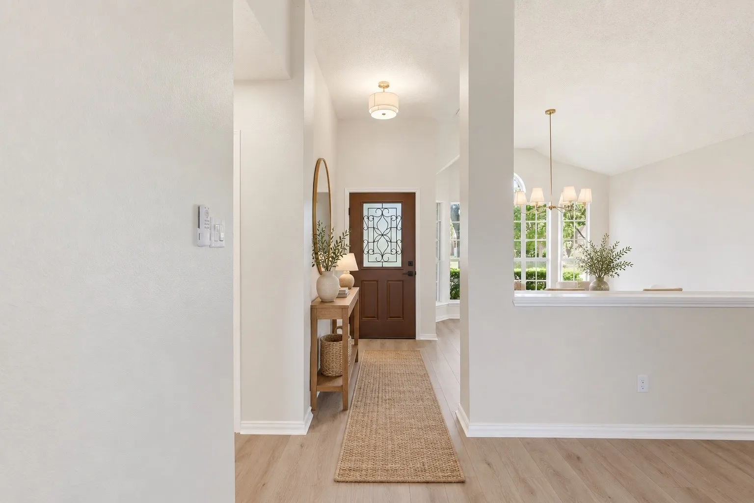 Wood-finish flooring throughout, decorative front door with leaded glass, recessed lighting, and a high vaulted ceiling with a chandelier