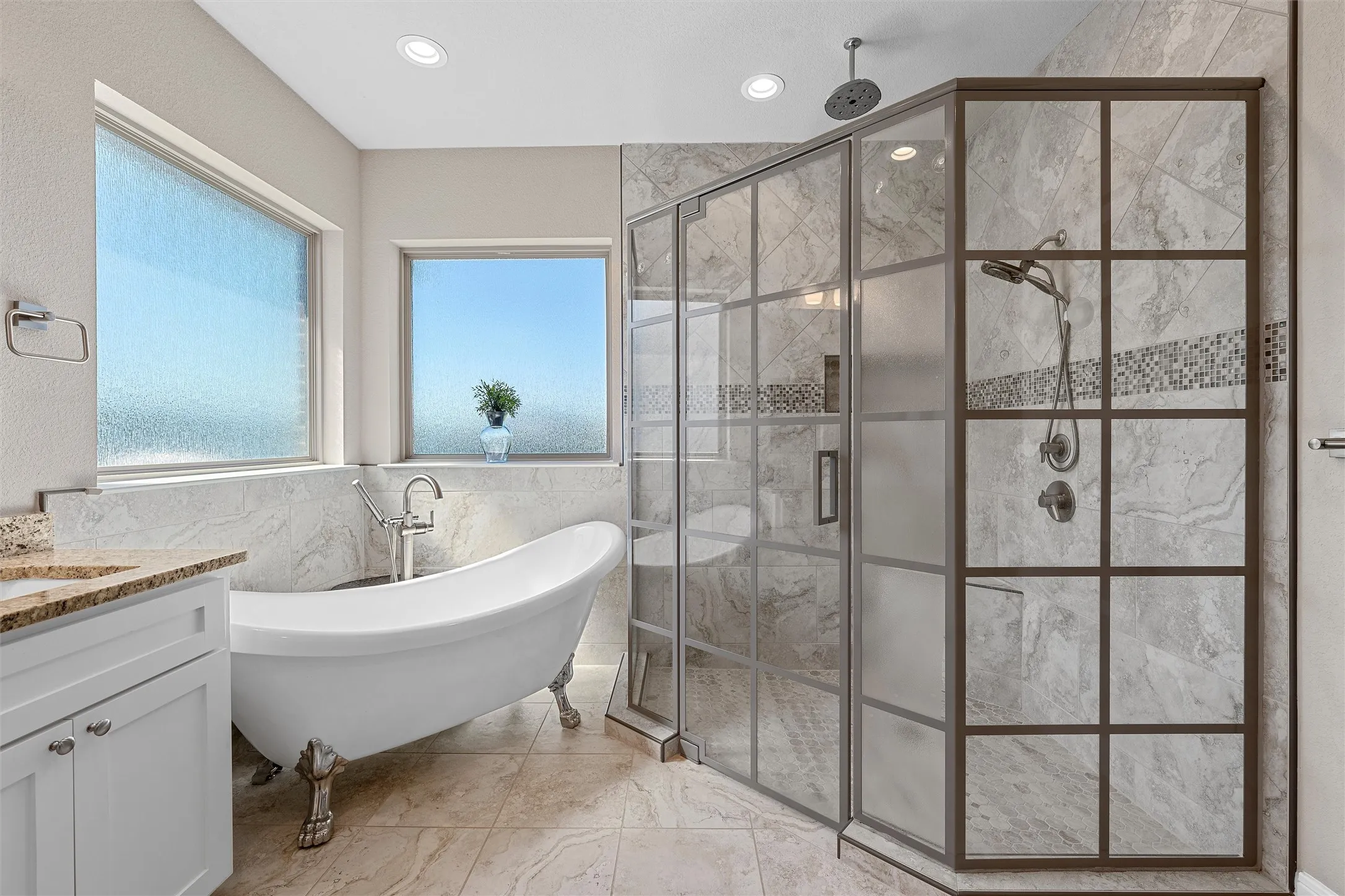 Freestanding clawfoot tub with a floor-mounted faucet, complemented by a walk-in shower featuring a grid-patterned glass enclosure and dual shower heads