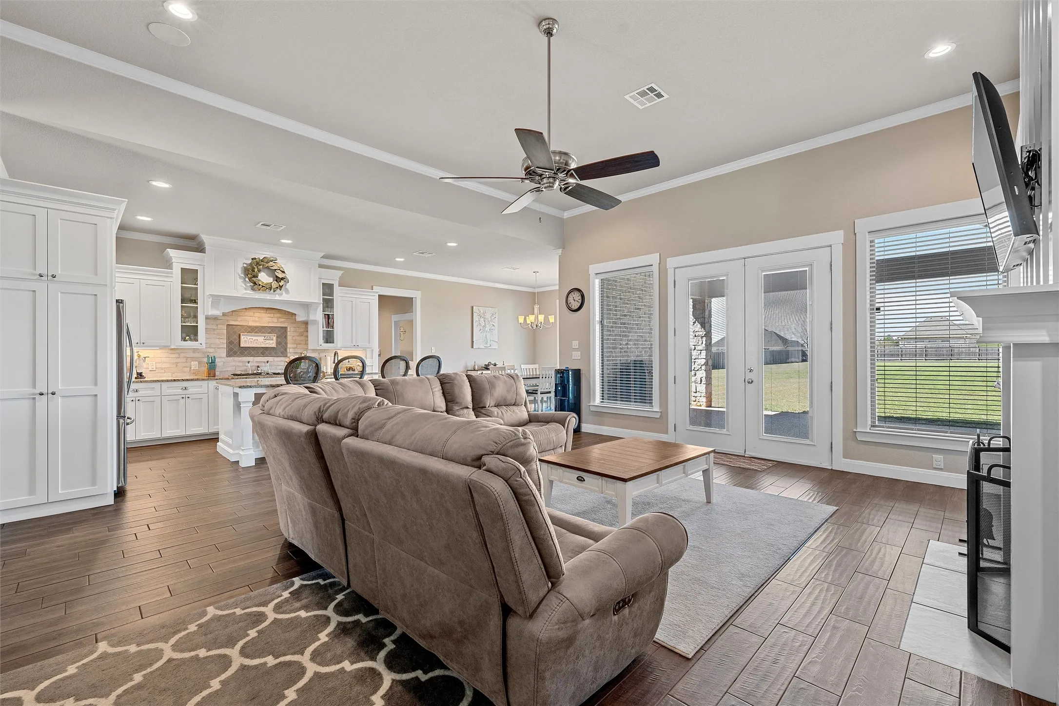 Spacious living area featuring wood-finish flooring, a fireplace with a white mantel, and a ceiling fan