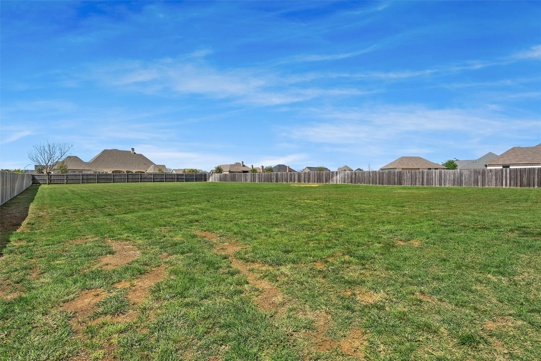 Expansive green lawn surrounded by a wooden privacy fence