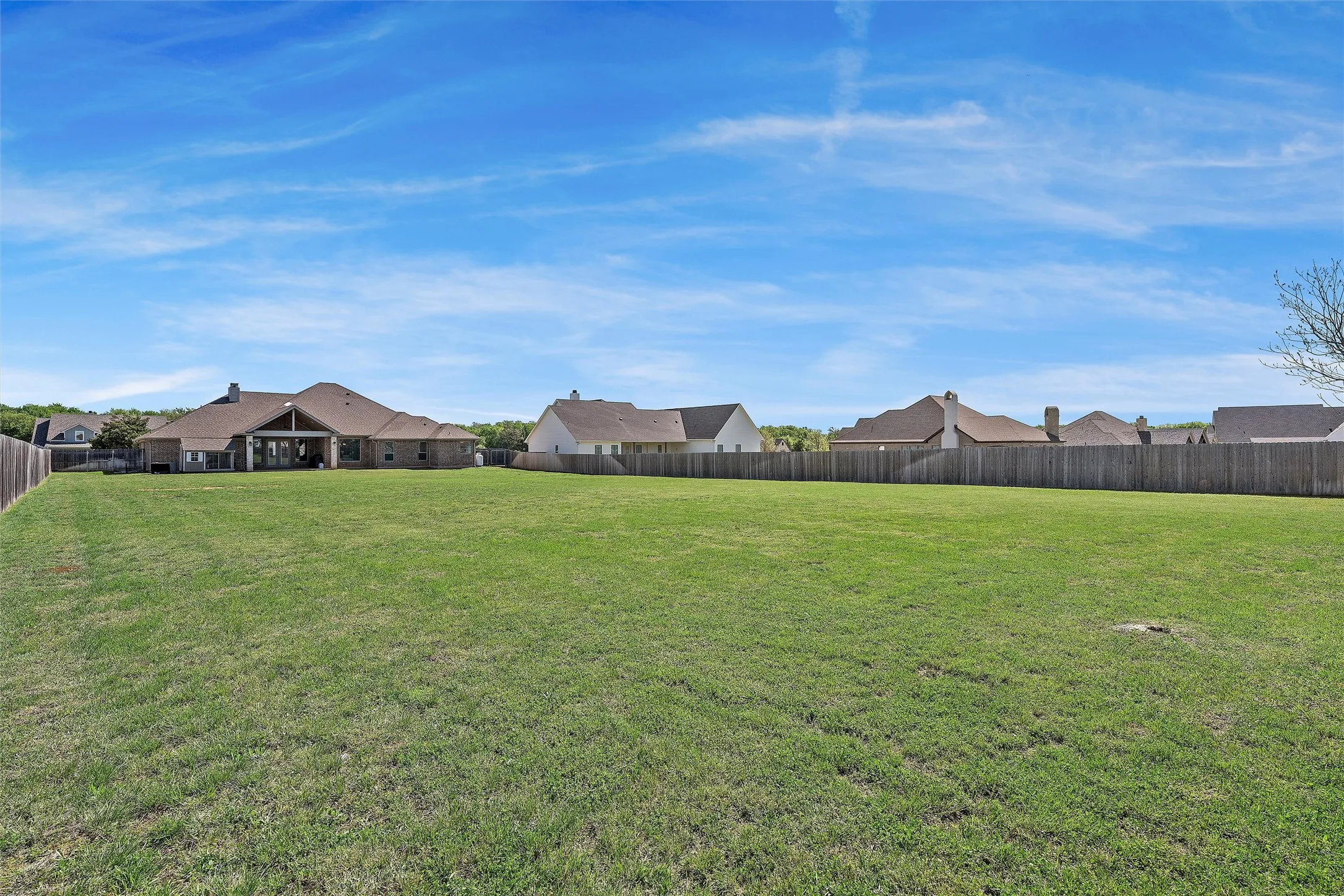 Expansive green space featuring a wooden privacy fence on three sides