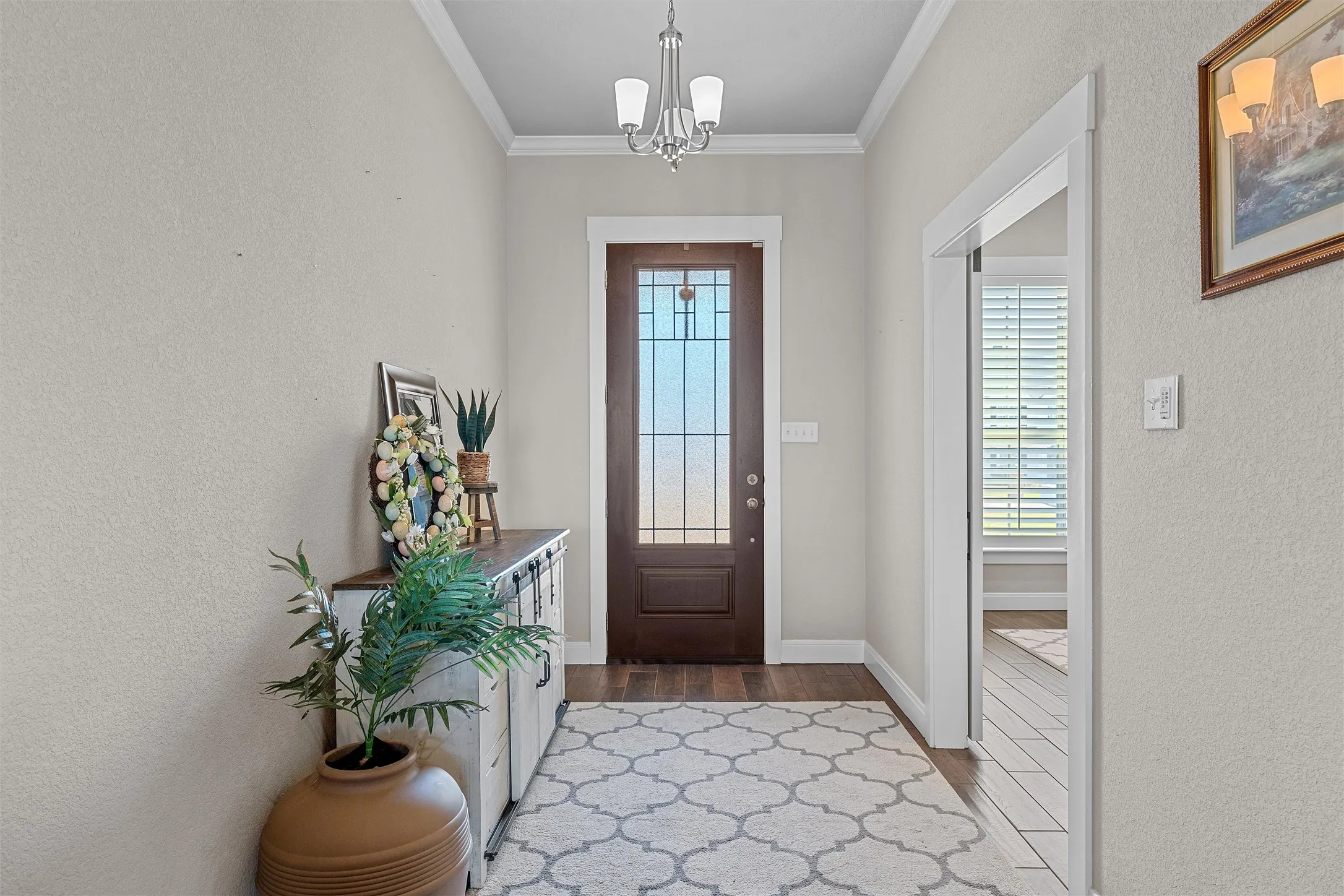 Entryway featuring wood-finish flooring, a decorative glass paneled door, and crown molding