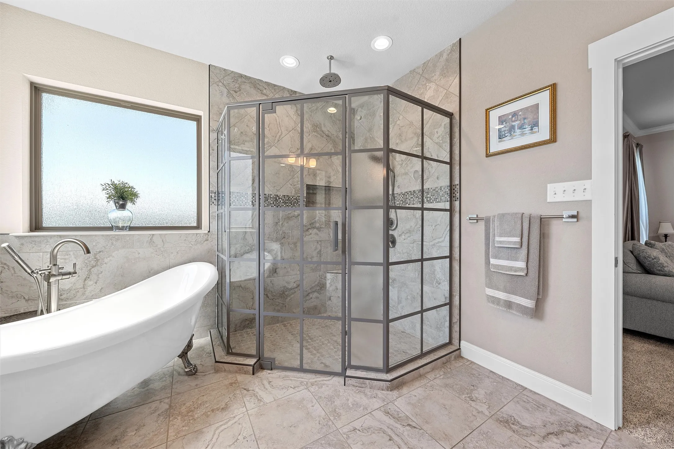 Bathroom featuring a freestanding clawfoot tub with a deck-mounted faucet, a corner glass-enclosed shower with a rain showerhead, and light-toned tile flooring