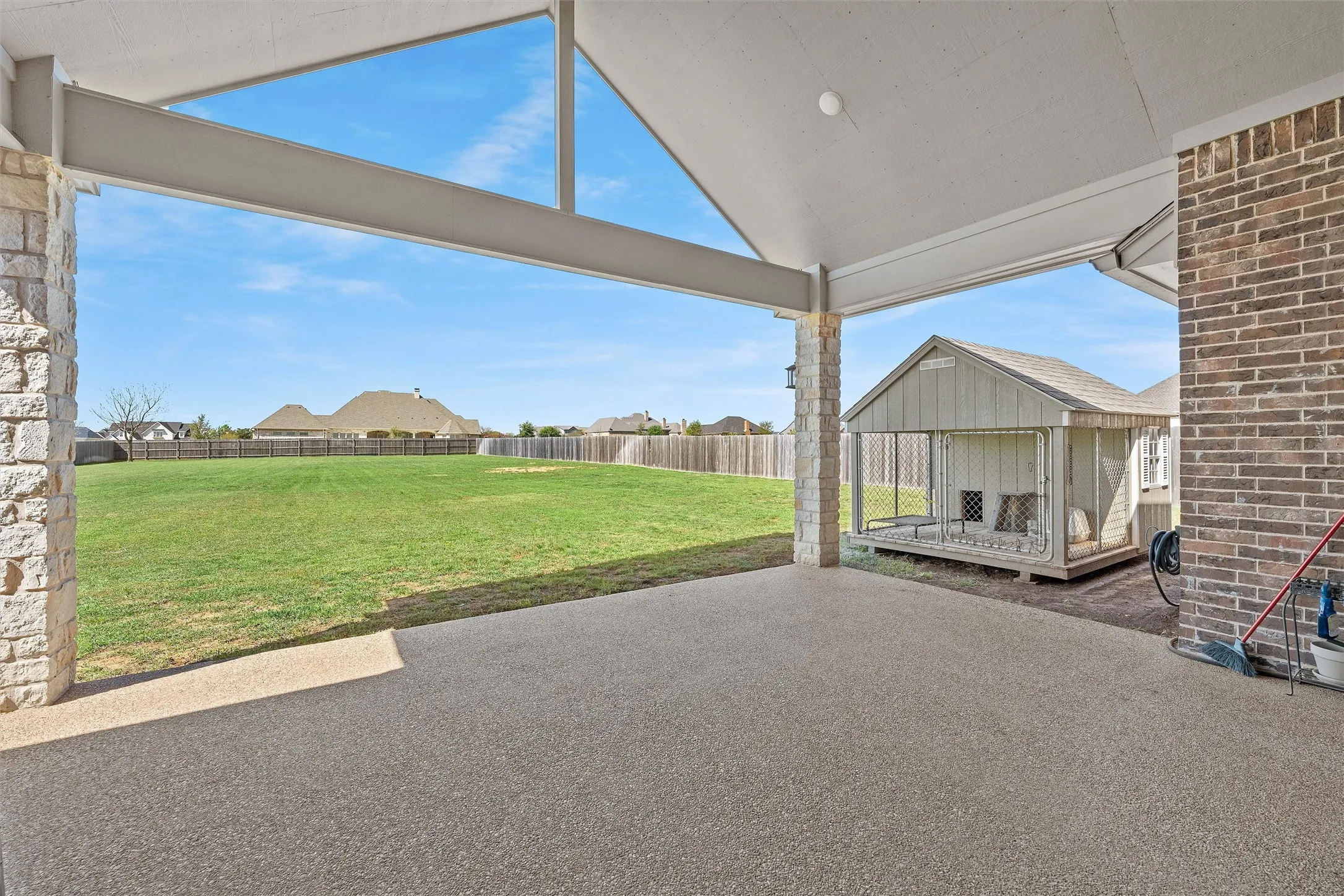 Covered outdoor patio with a textured concrete surface and stone-clad support pillars