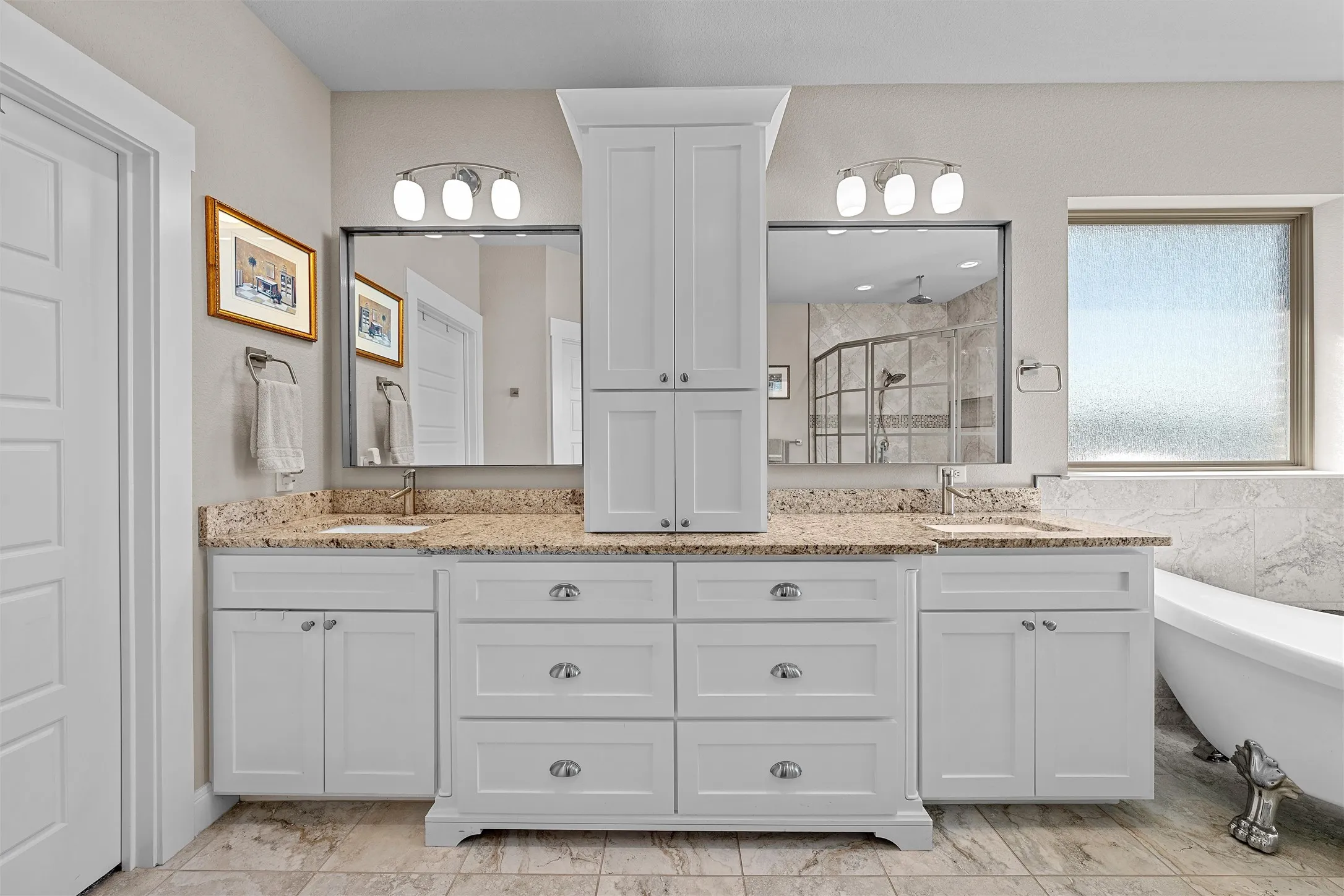 Double vanity with white cabinetry, granite countertops, dual sinks, and polished chrome hardware
