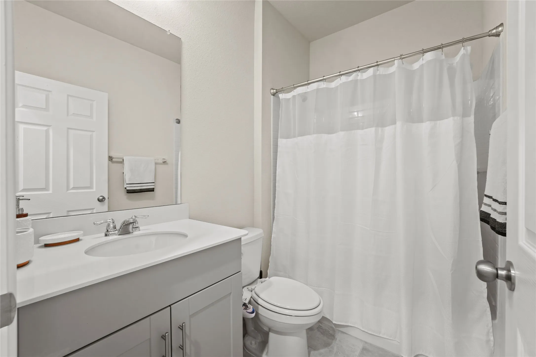 Bathroom with vanity, toilet, and a shower with shower curtain