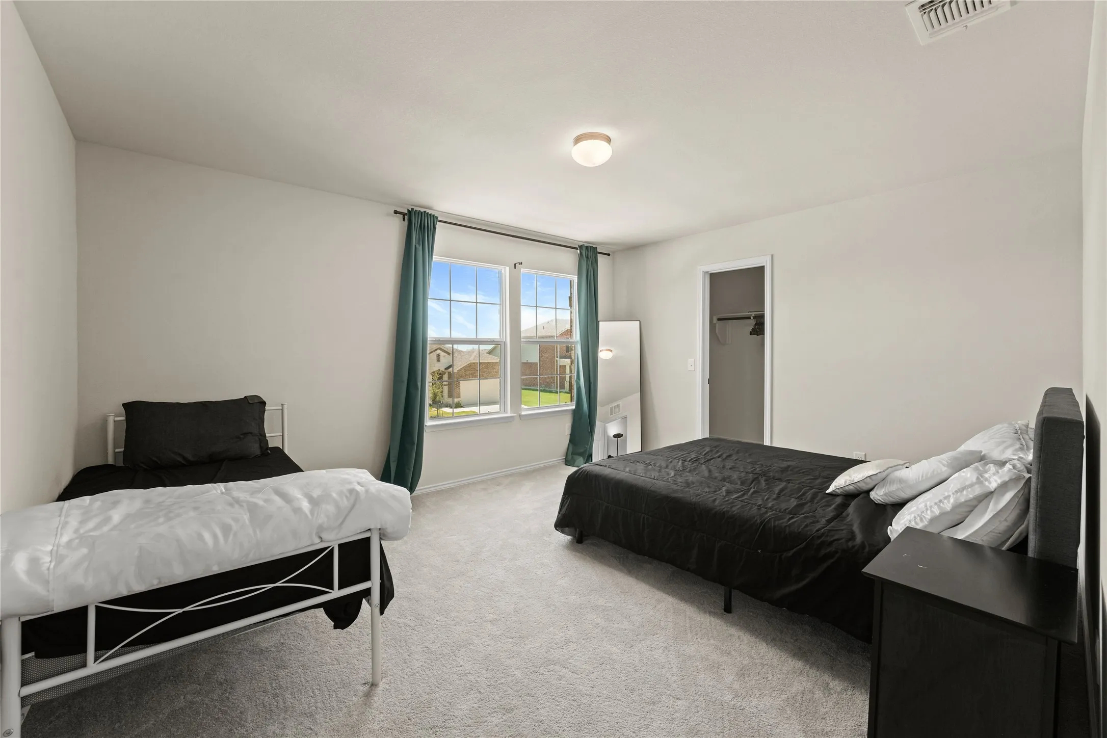 Carpeted bedroom featuring a closet and a spacious closet