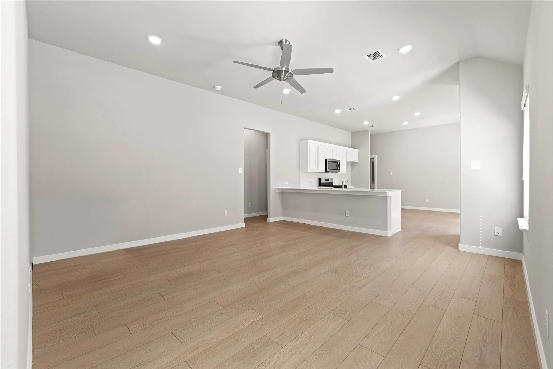 Unfurnished living room featuring ceiling fan and light hardwood / wood-style floors