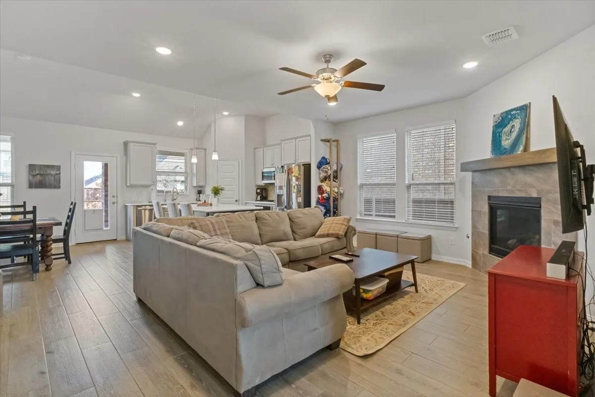 Living room with lofted ceiling, a tile fireplace, light wood-style flooring, recessed lighting, and visible vents