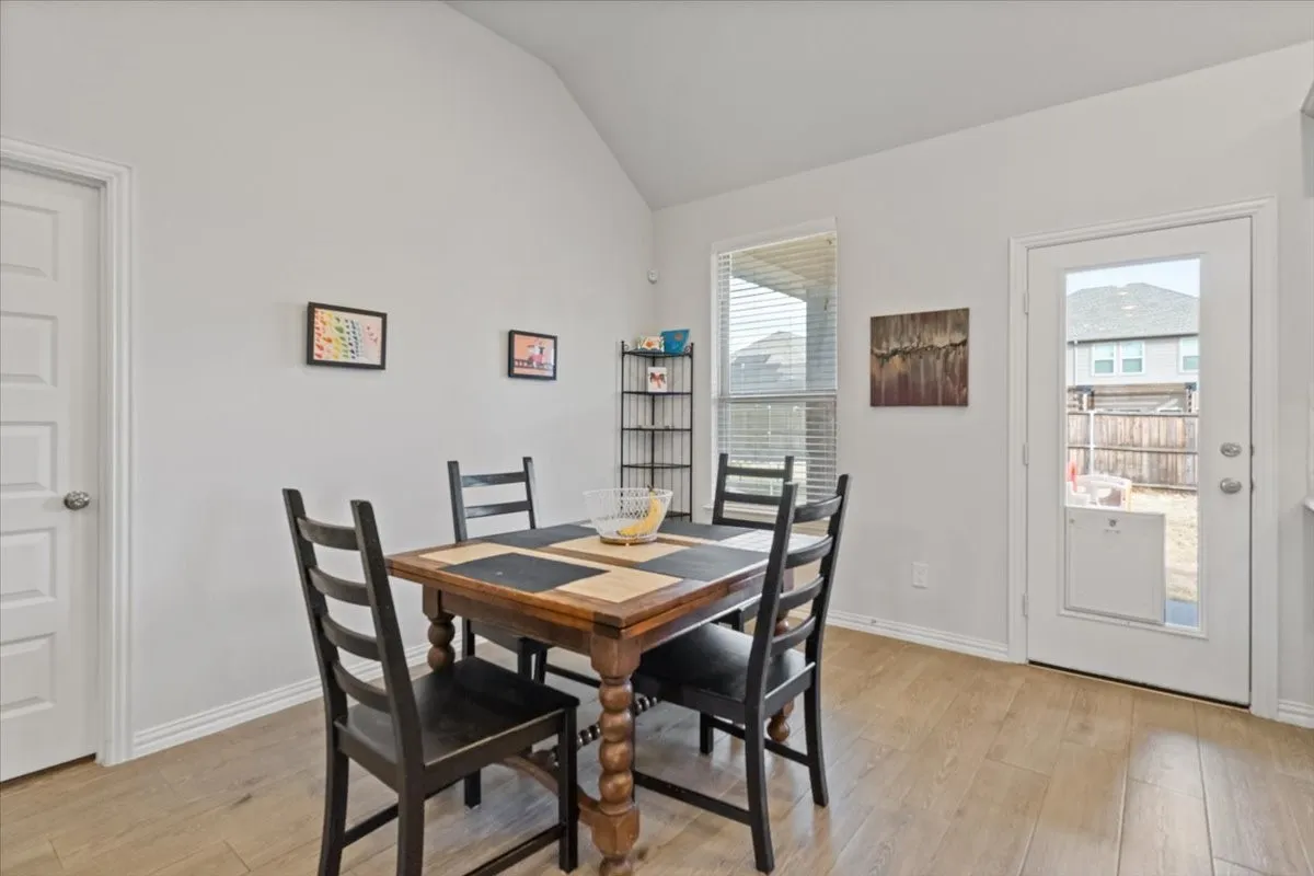 Dining room with vaulted ceiling, light wood-type flooring, and baseboards