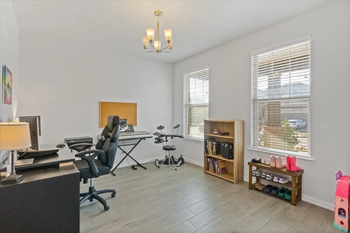 Office space with baseboards, light wood-type flooring, and a notable chandelier
