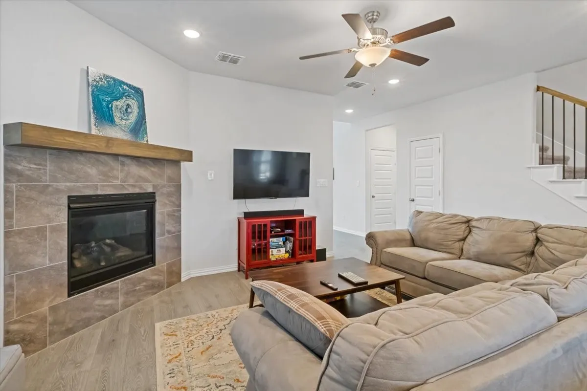Living area with a fireplace, recessed lighting, visible vents, light wood-type flooring, and stairs