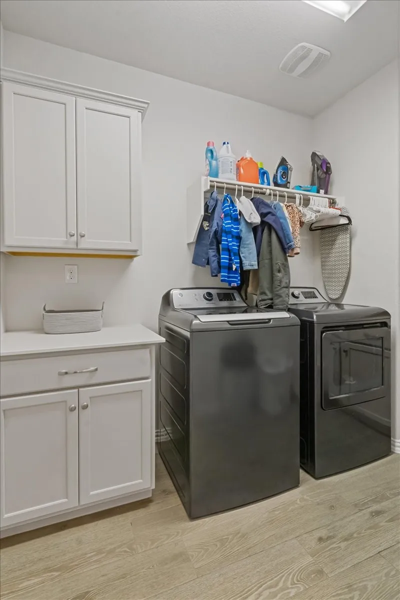 Washroom featuring cabinet space, independent washer and dryer, visible vents, and light wood finished floors