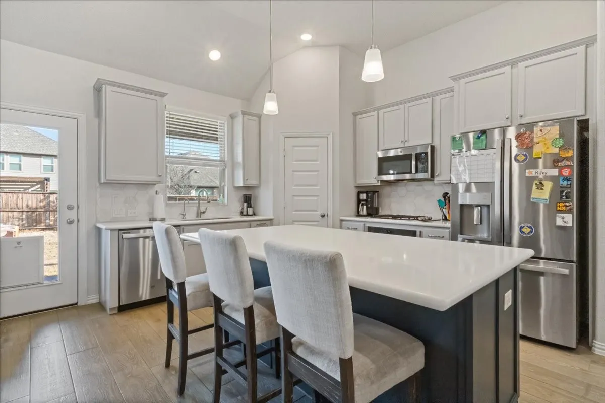 Kitchen with a center island, stainless steel appliances, light countertops, pendant lighting, and a sink