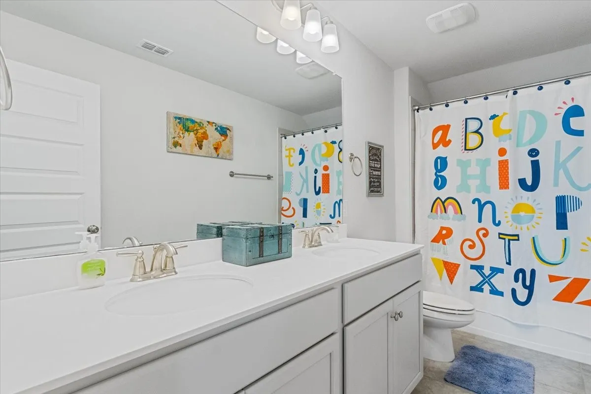 Bathroom with visible vents, a sink, toilet, and shower / bathtub combination with curtain
