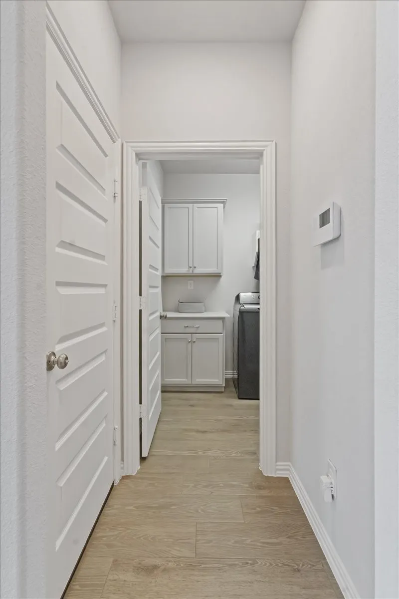 Corridor featuring washer / dryer, light wood-style flooring, and baseboards