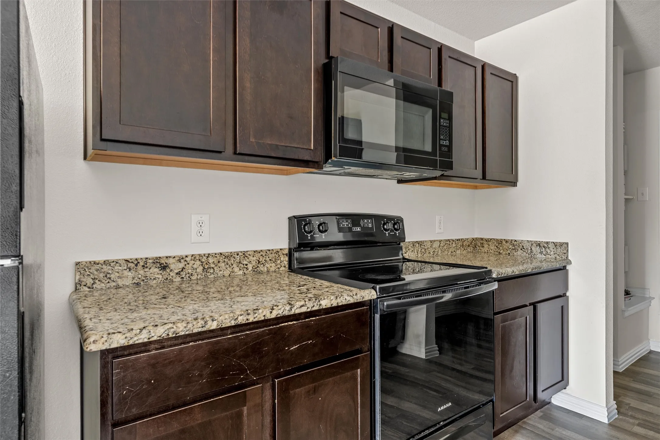 Dark wood-finish cabinetry with a black microwave and electric range