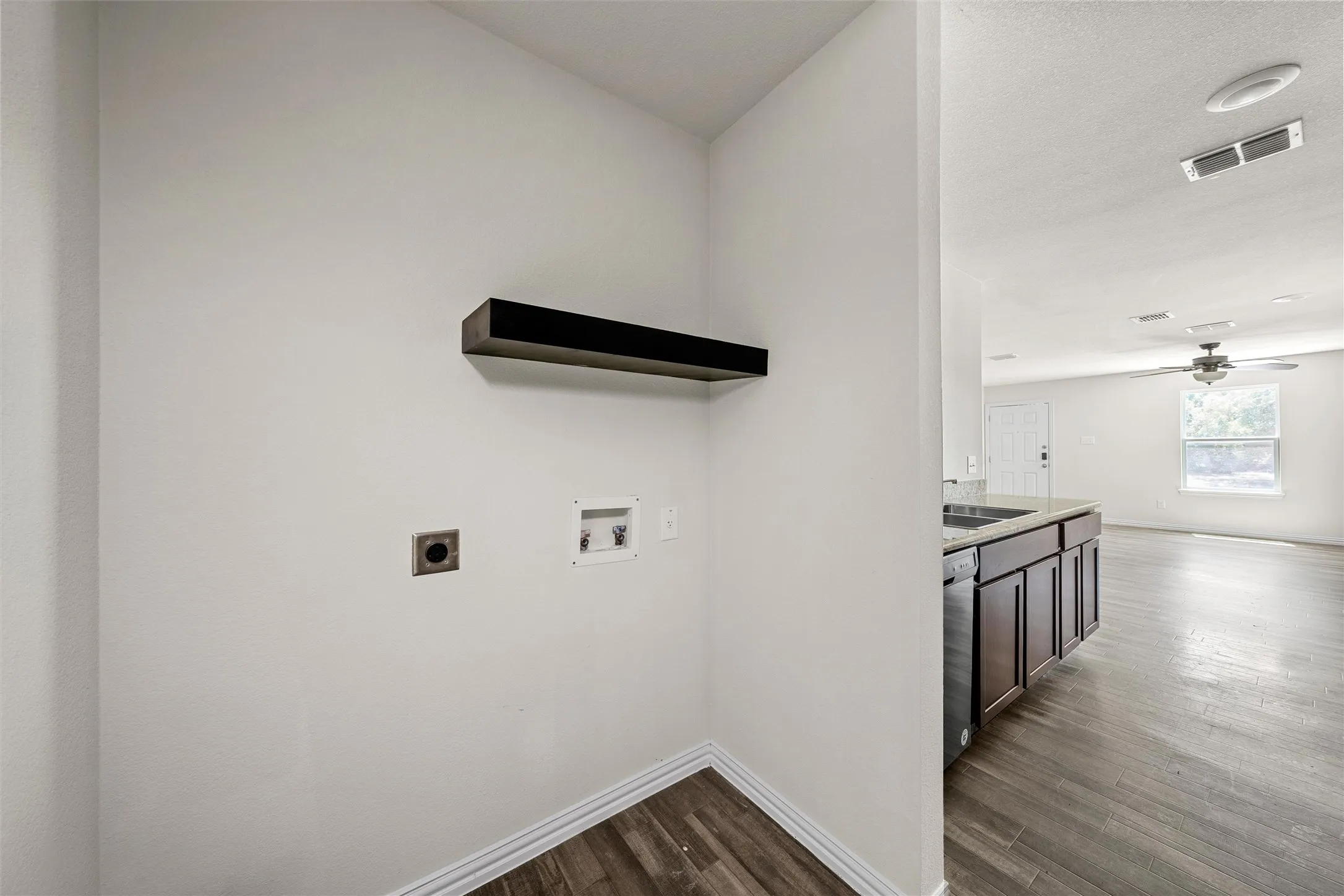 Laundry area with a built-in floating shelf and wood-finish flooring