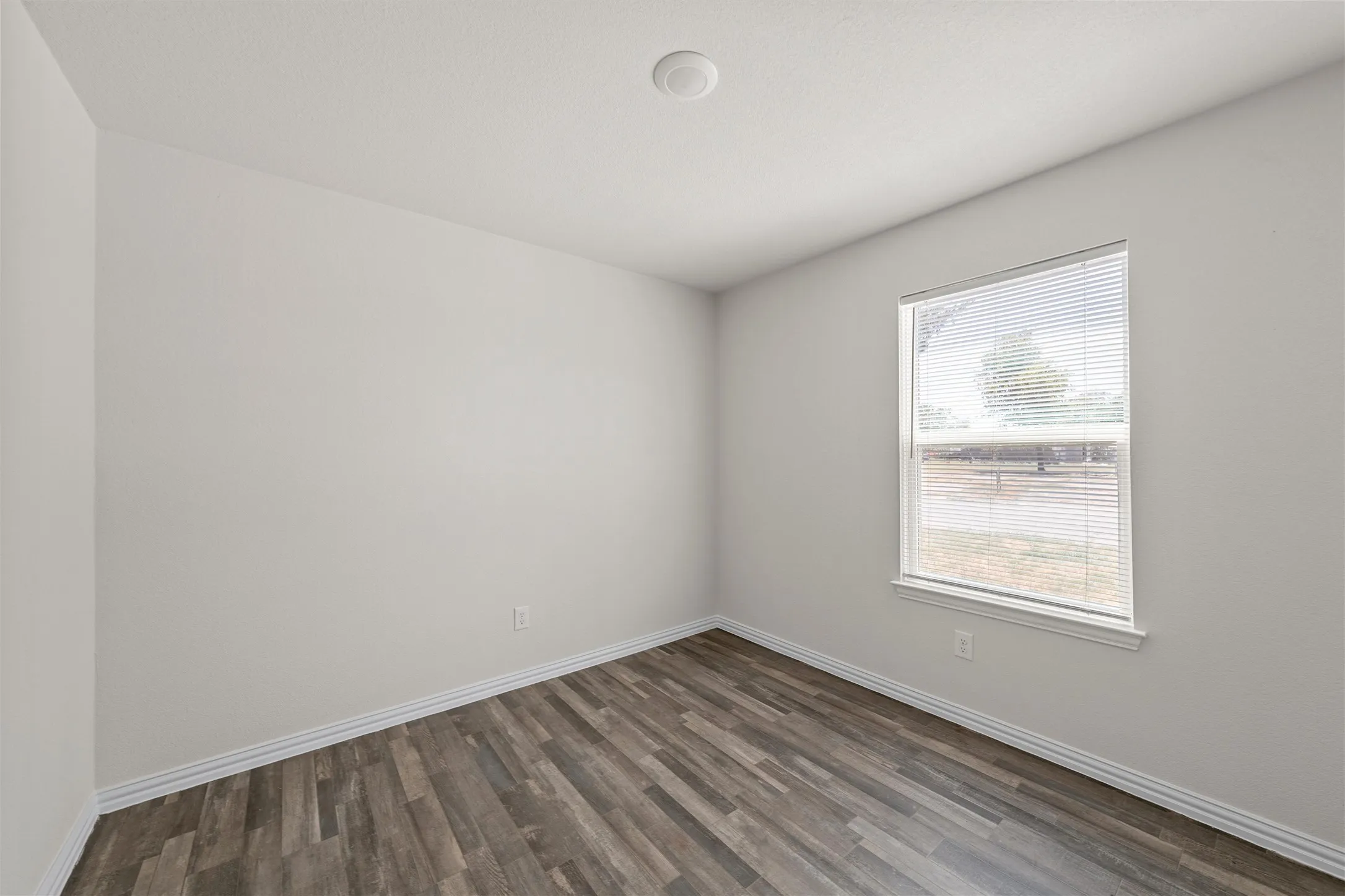 Recessed ceiling light, wood-finish flooring, white wall paint, window with blinds, white trim