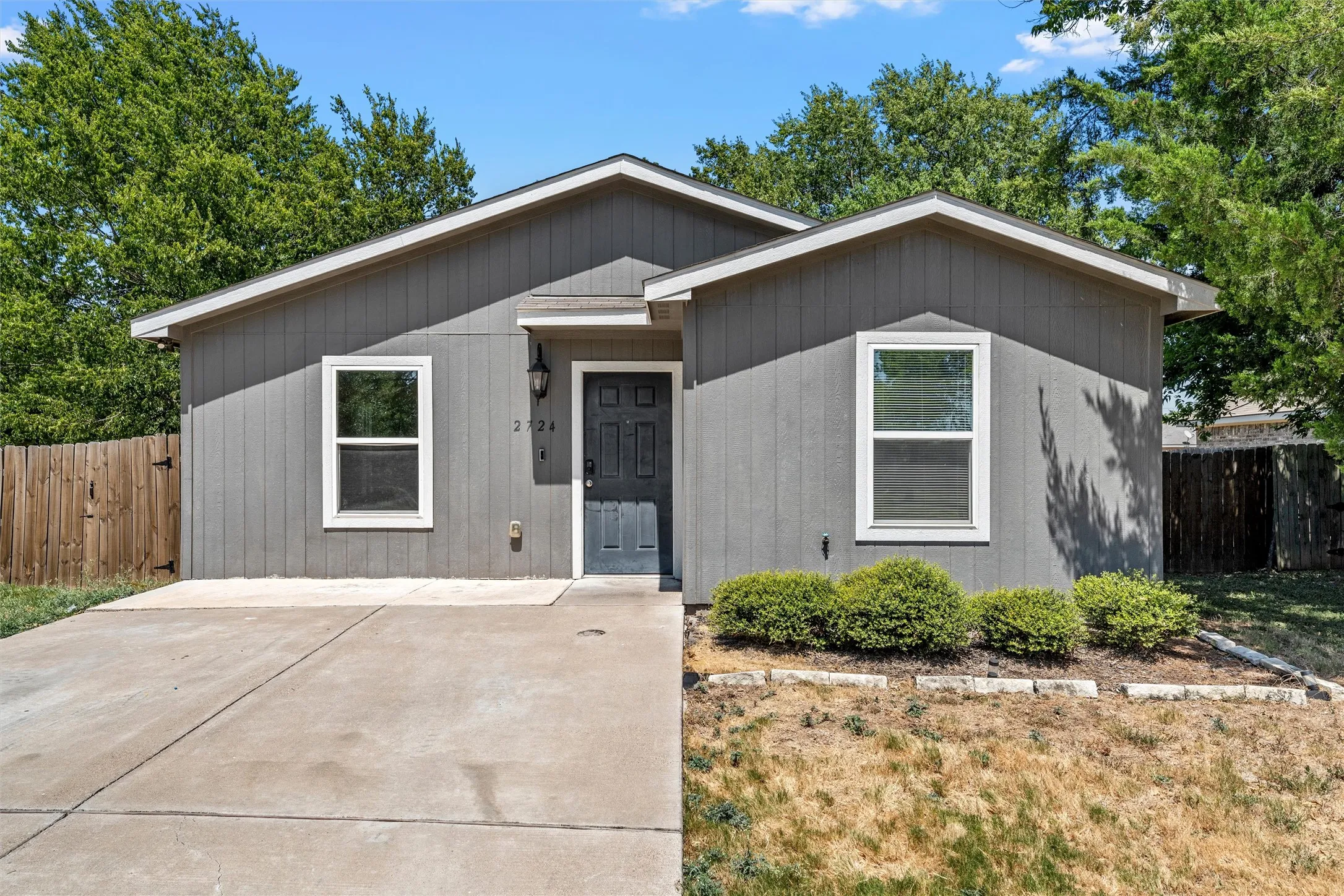 Gray siding exterior with white trim, a dark gray entry door, and a concrete driveway