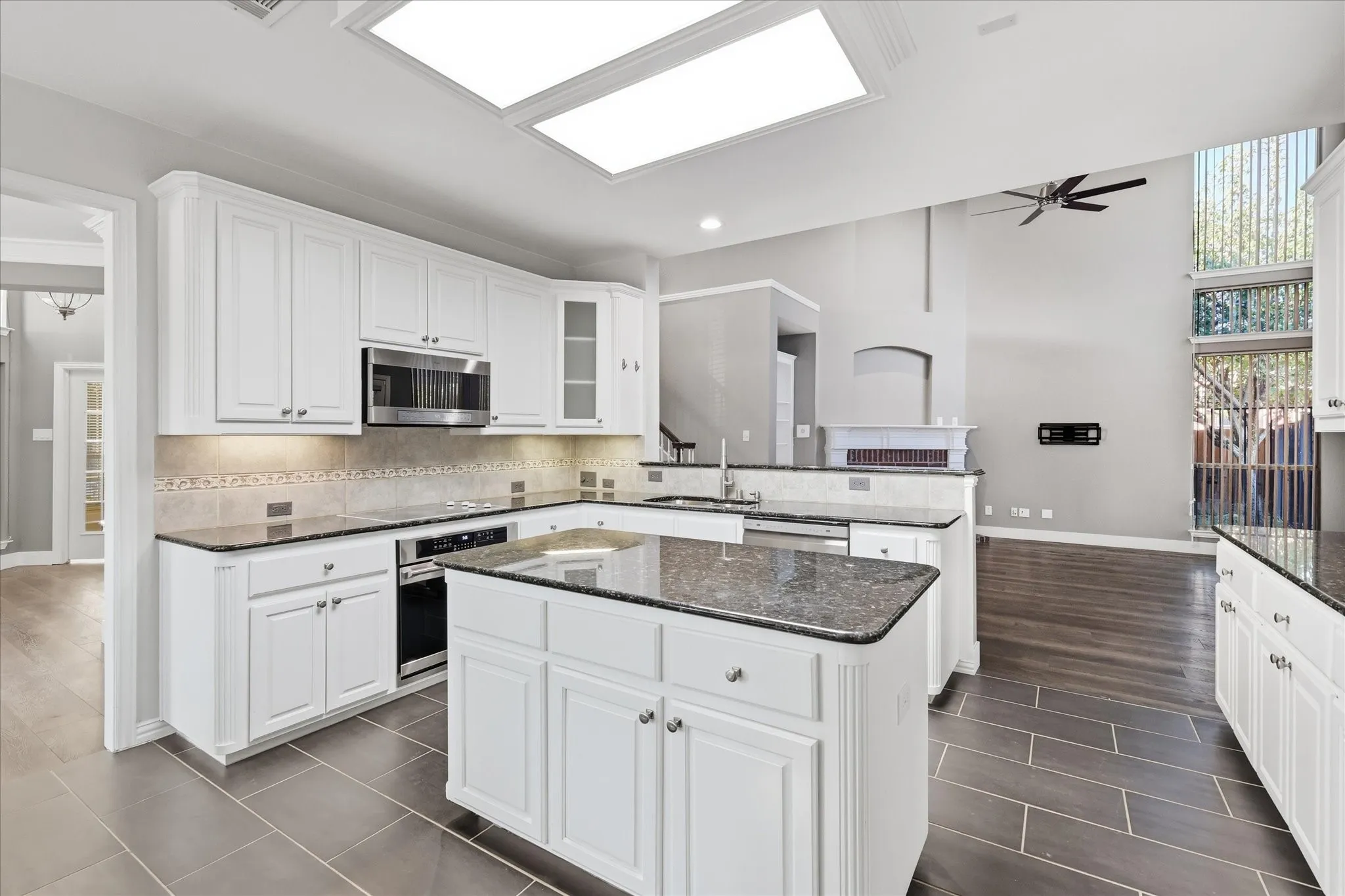 Kitchen featuring white cabinetry, dark stone countertops, stainless steel appliances, and tile flooring
