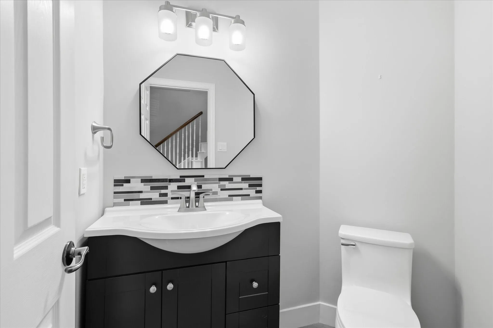 Vanity with dark wood-finish cabinetry, white countertop, and mosaic tile backsplash